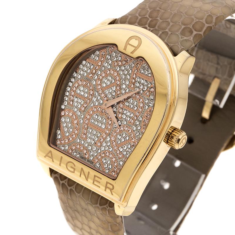 Boasting of a gold-plated stainless steel body, this Verona watch from Aigner features a case diameter of 39mm. It comes with a logo shaped printed dial with brown markers. Powered by quartz movement, this watch comes fitted with a textured brown