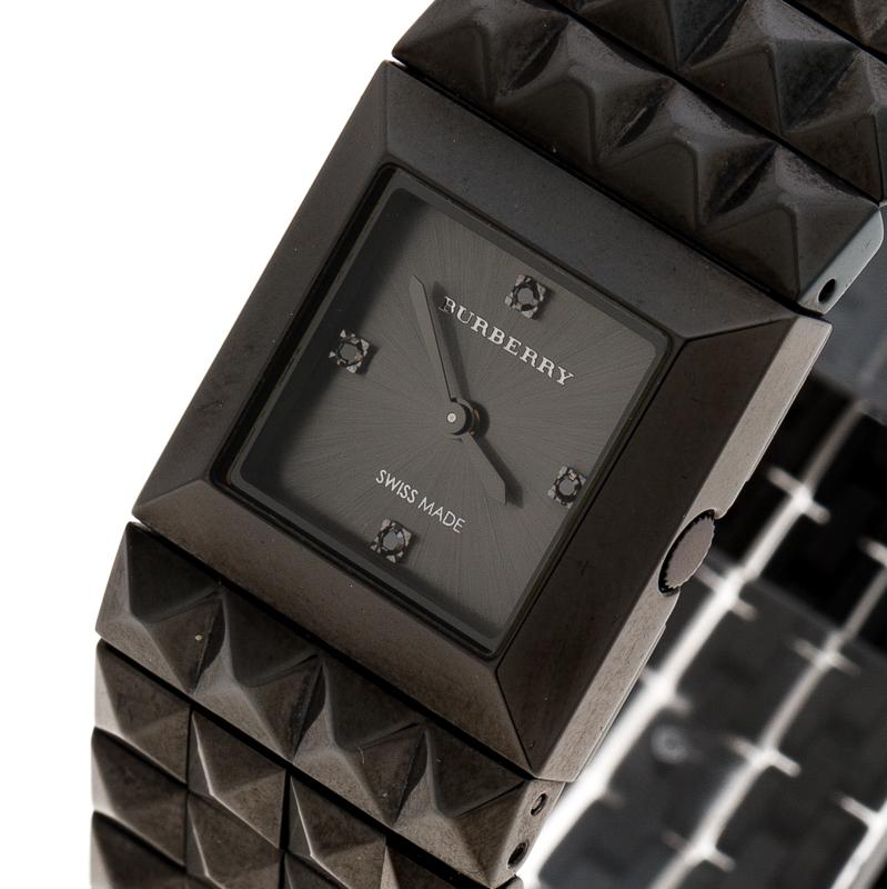 This watch from Burberry stands for quality and sophistication. The watch is crafted from blackened stainless steel and the square case is held by a bracelet that has 4 rows of pyramid studs. It is powered by quartz movement and on its black dial,