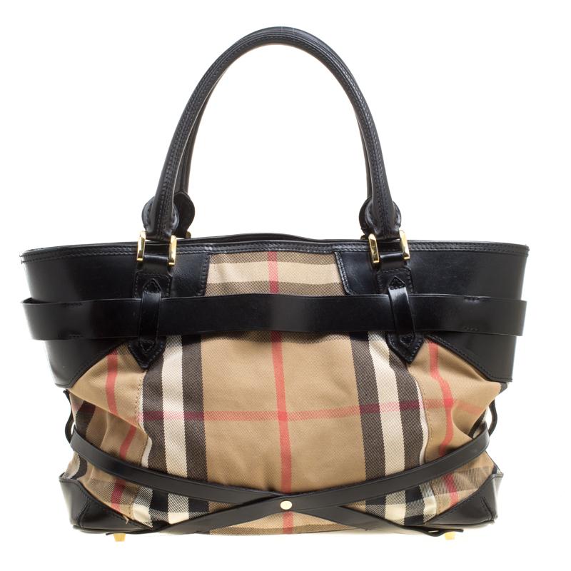 The design of this tote from Burberry makes it a beautiful accessory to own. It has been crafted from signature house check canvas and black leather. The fabric lined interior is spacious enough to hold your everyday essentials. The bag comes with