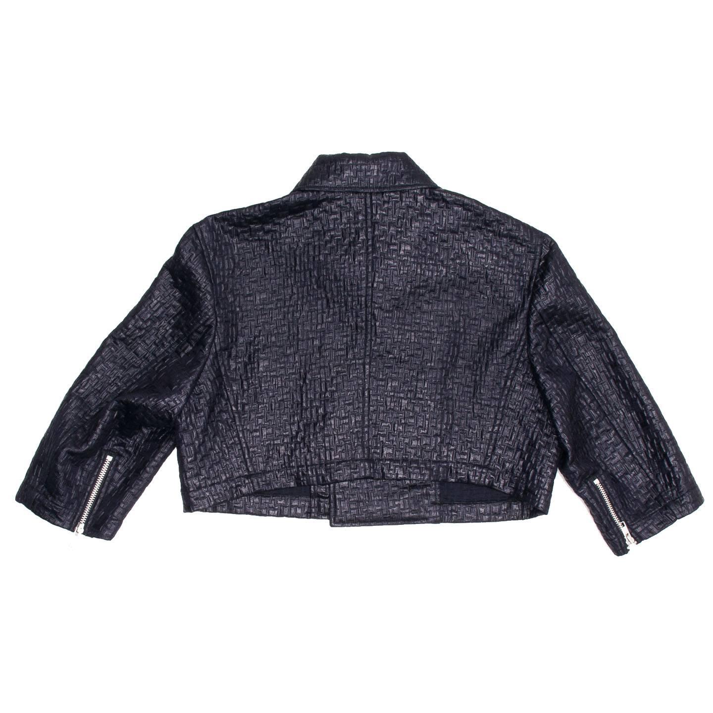 Ink blue cropped motorcycle jacket in an embossed looking textured fabric. The zips on cuffs, pockets and front opening are chunky and silver to contrast the soft elegant and sheeny fabric. The sleeves are 3/4 length, simple and elegant. Made in