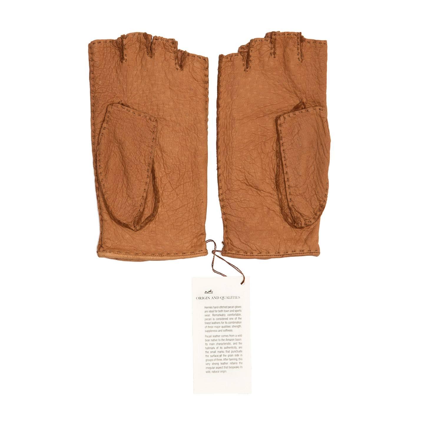 Tan pecari leather driving style fingerless gloves. Tone-on-tone top stitchings and perforated Hermes logo decorate the textured soft leather and a snap button closes the wrist at front.

Size  8 General sizing

Condition  Excellent: never worn