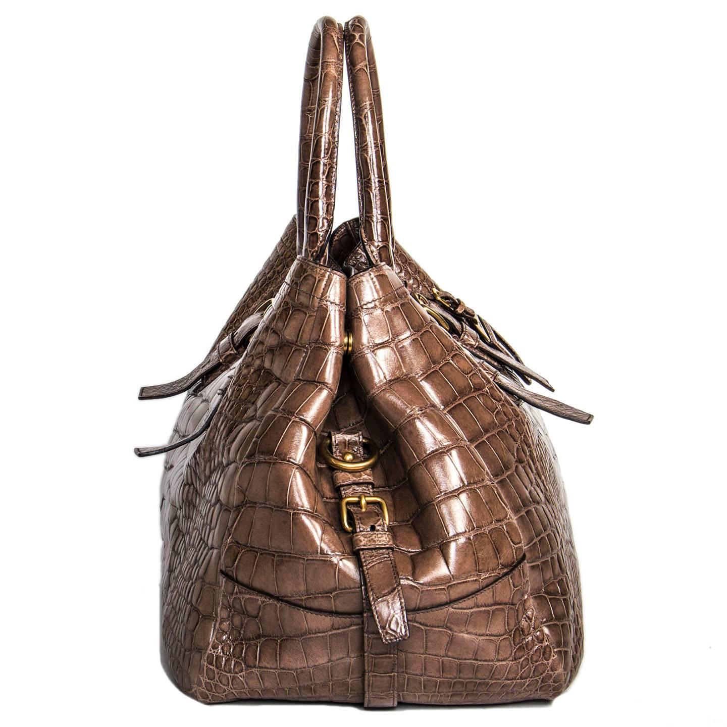 Grey/brown beautifully crafted crocodile large bag with Prada brushed gold metal letters. Front, back and sides are also enriched by buckles and straps detailing. A gold metal snap fastens the bag as well as the sides to make the bag wider. Special