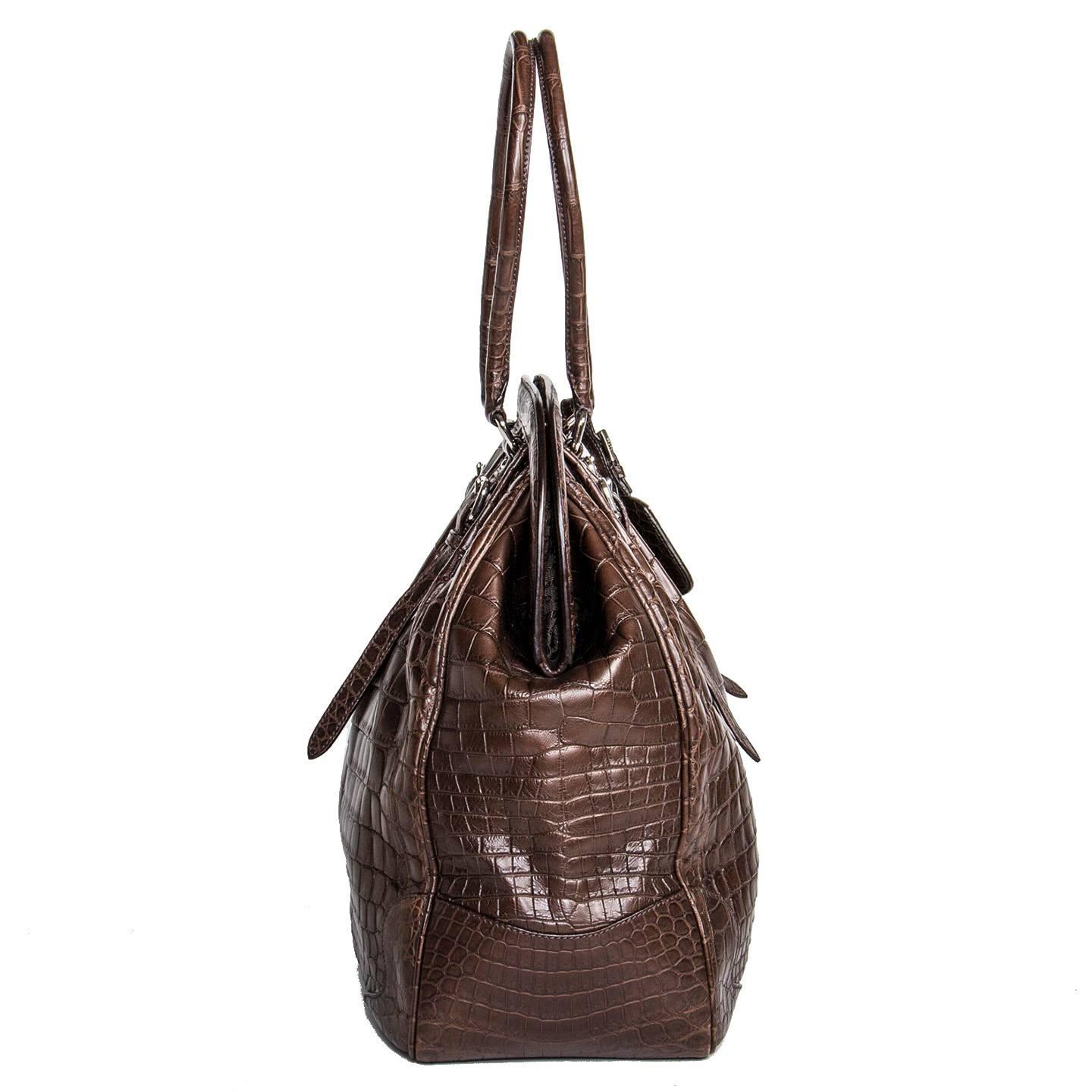 Chocolate brown crocodile bag with a vintage classic design, style reference number BR 3511. Front and back are enriched by extra straps with little belt buckles and pleats that emphasize the round volume of the bag. The front of the bag is also