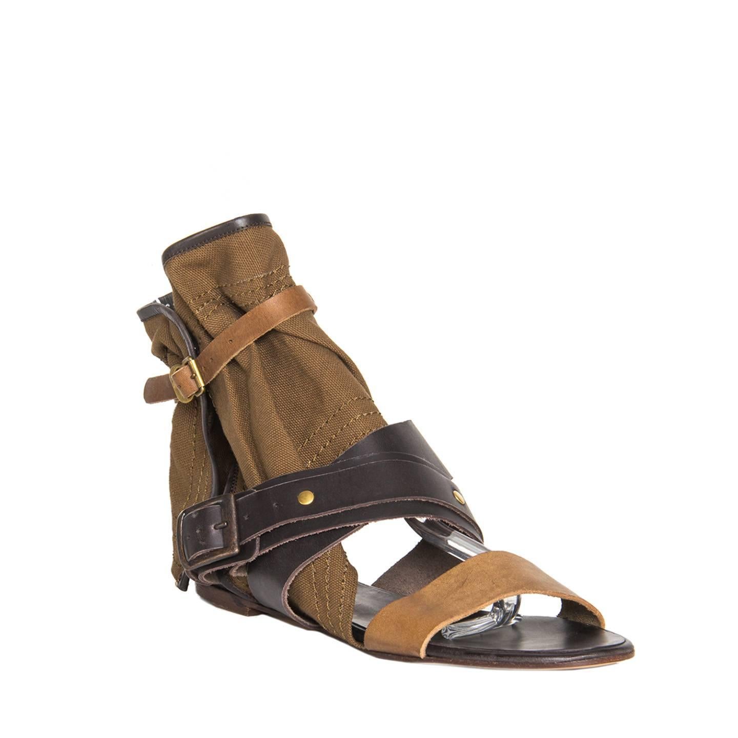 Dark brown and cognac color leather gladiator sandals with open front and a wide olive canvas cuff. The canvas is enriched by brown leather binding on profiles, tone-on-tone top stitches and it fastens with a snap buttons, while the leather straps