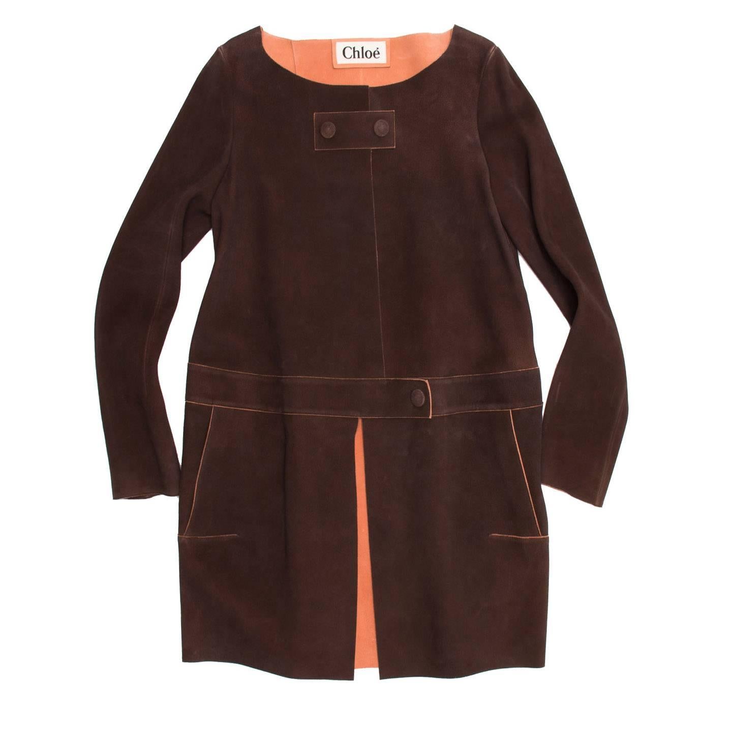 Chocolate brown deerskin suede coat with peach color inner face and seams profiles to create a beautiful contrast with the brown and enhance the 60's style flair. It's a knee length coat with a wide round collar and broad waistband at lower waist