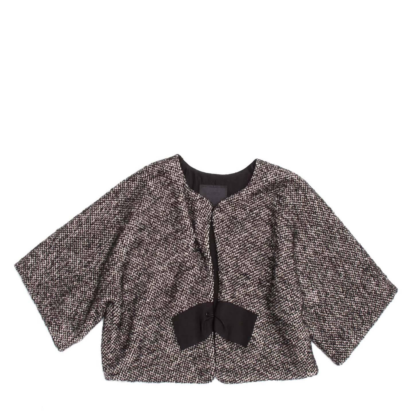 Lanvin 2008. Cropped flay-away black and grey tweed jacket with round neck. A black bow grosgrain ribbon embellishes the big hook closure and the kimono sleeves are 3/4 length.The outer layer is a bland of wool/alpaca/cotton/mohair and the black