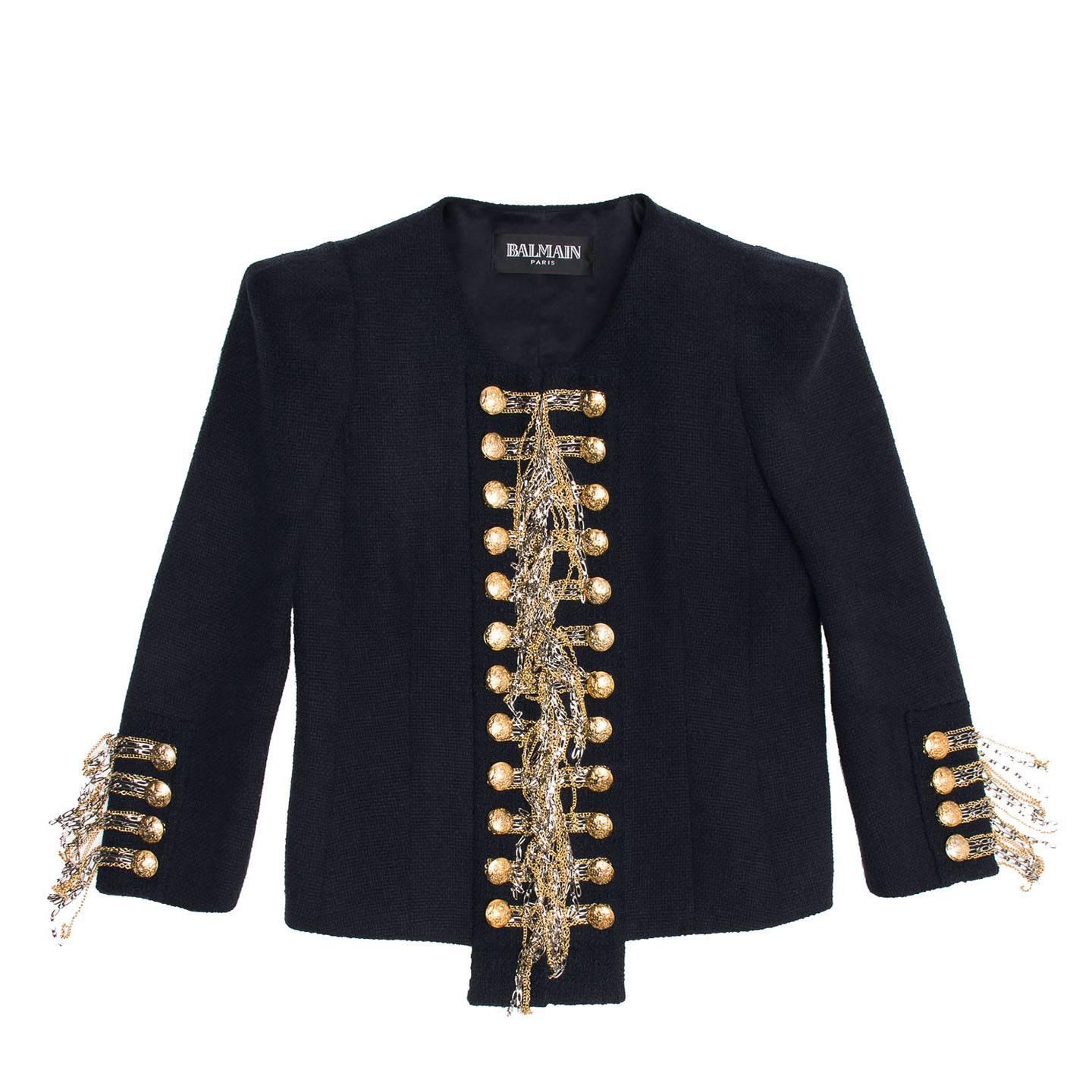 Blue silk & cotton woven cropped jacket with gold and silver chains to create a unique military style statement detail. The neckline is round and elegant and the jacket fastens with invisible hooks at center front where the dangling chains meet