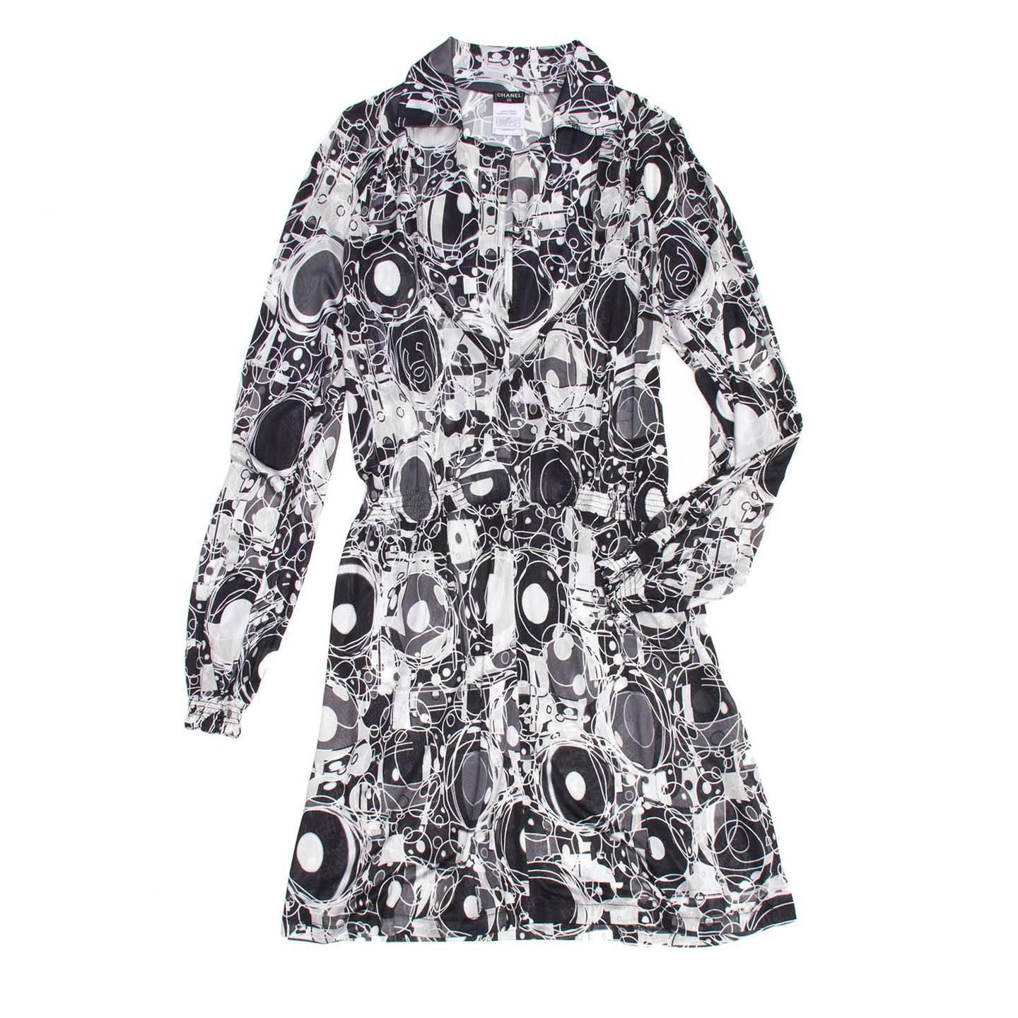 Black & white silk jersey shirtdress with abstract and CC Chanel logo print. The dress has an above knee length, a deep V-neck with lapel and a concealed zipper from under the collar to the hips. The waist is highlighted by a band of elastic