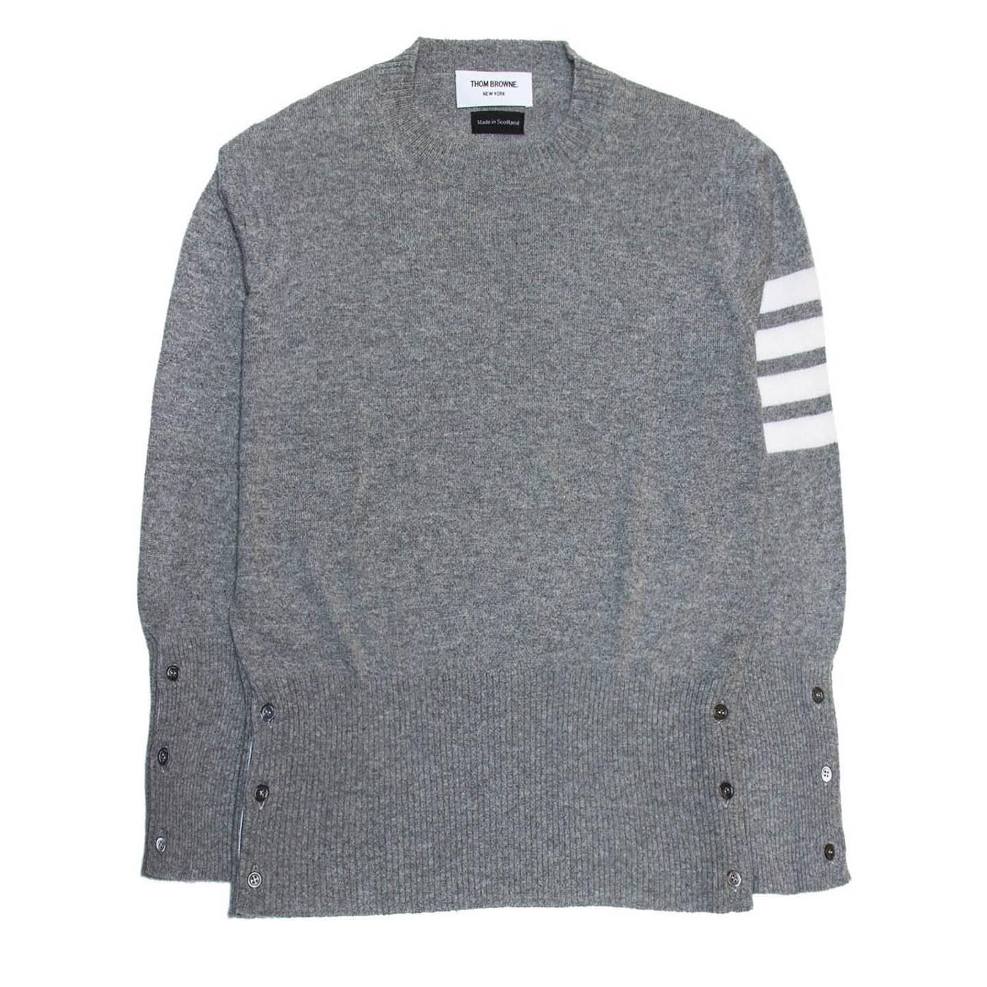 Grey cashmere crew neck pullover with four ivory jersey style stripes on left top sleeve. Hem and cuffs fasten with dark grey buttons and show a blue/red/white striped ribbon when open. Made in Scotland. Made for Men Worn by Women too.

Size