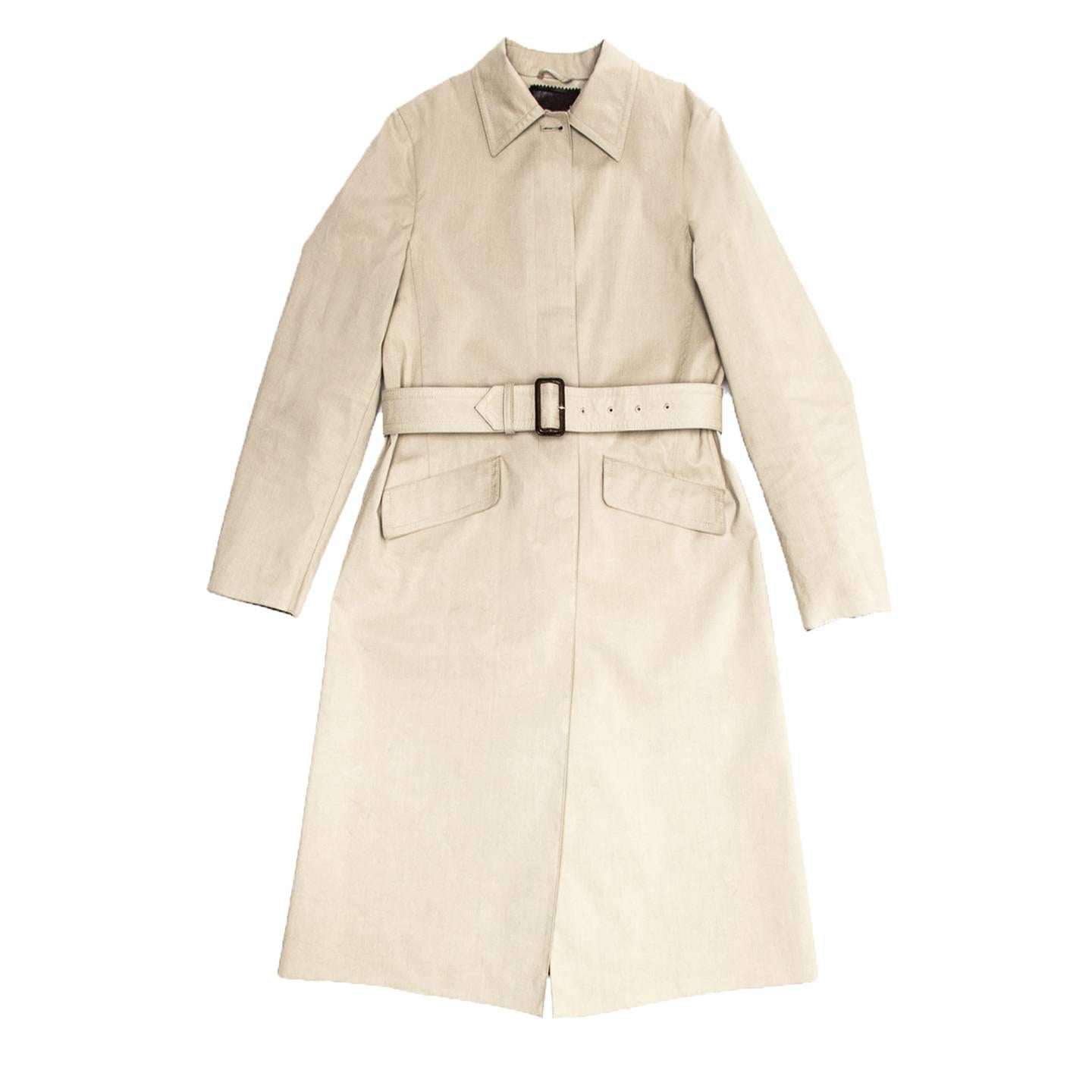 Khaki cotton traditional raincoat with straight fit and below knee length. It is a single breasted coat that fastens with chocolate brown buttons hidden under the front panel, it has a peter pan collar and slanted flap pockets at hips. The sleeves