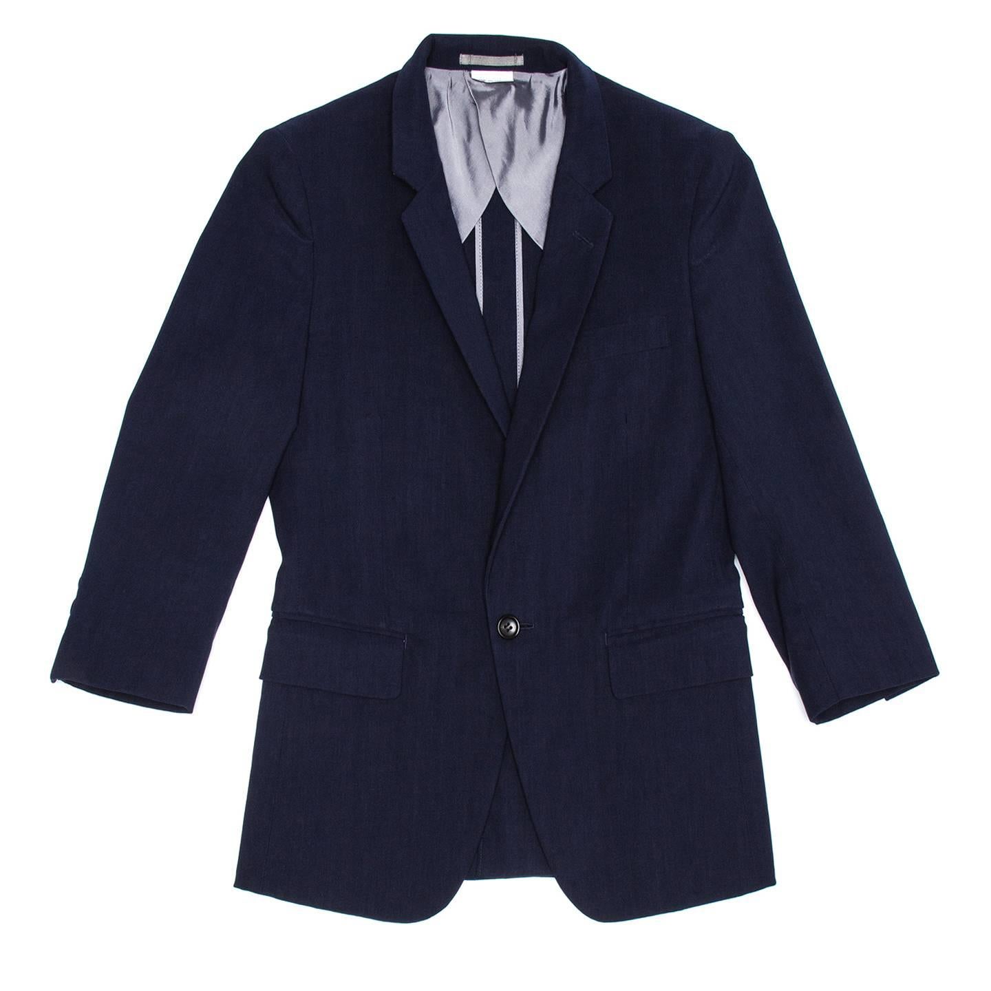 Navy blue linen stretch blend very fitted jacket with 3/4 sleeves, single vent at back and single button at front. The blazer is worn with the neck standing showing the grey under collar and the lapel flat and fastened at neck with a button. Comme