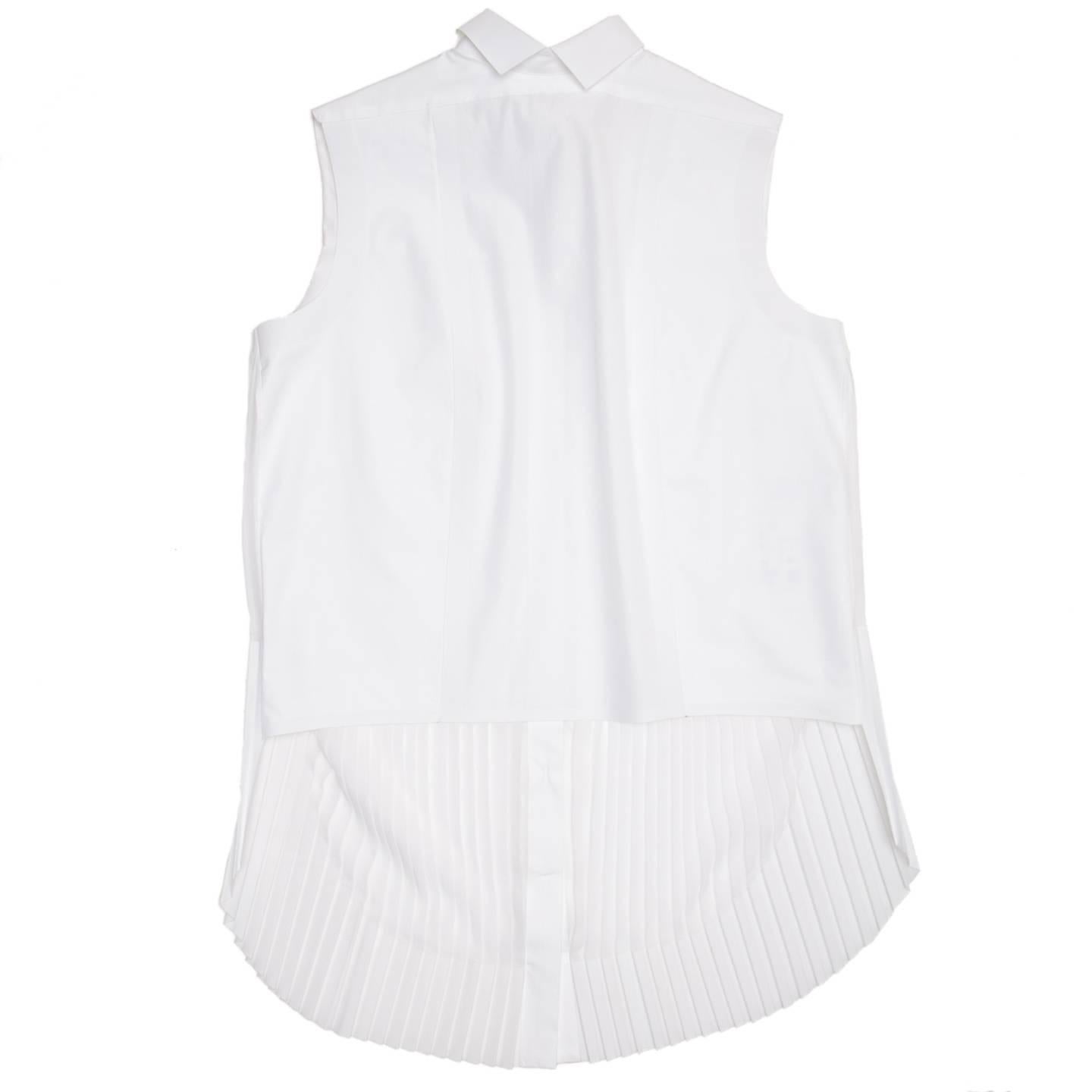 White shirt with a small peter pan collar with points at central back to duplicate the front. The back body is fitted, short and made of pure cotton. The front top part is made of a double layer of cotton to create rigidity, as well as the button