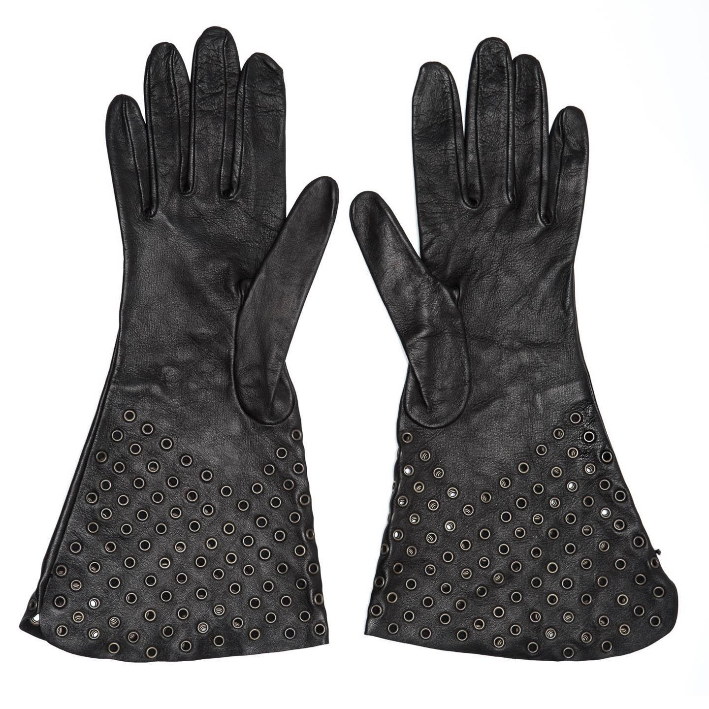 Black lambskin leather long gloves punctuated with brass eyelets. Crafted in France.

Size  7