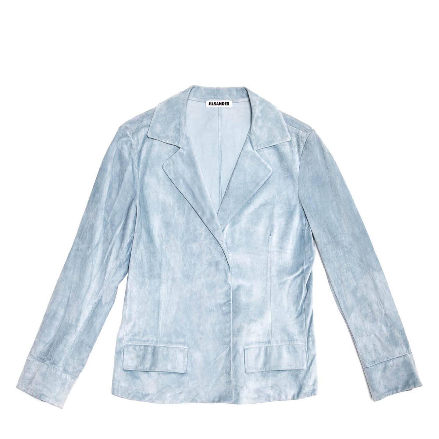 Powder blue velvet soft suede cropped jacket with medium size lapel, flap pockets and two hidden snap buttons fastening the front. The back is plain and the cuffs are enriched by a shirt style band and they fasten with invisible snap buttons to