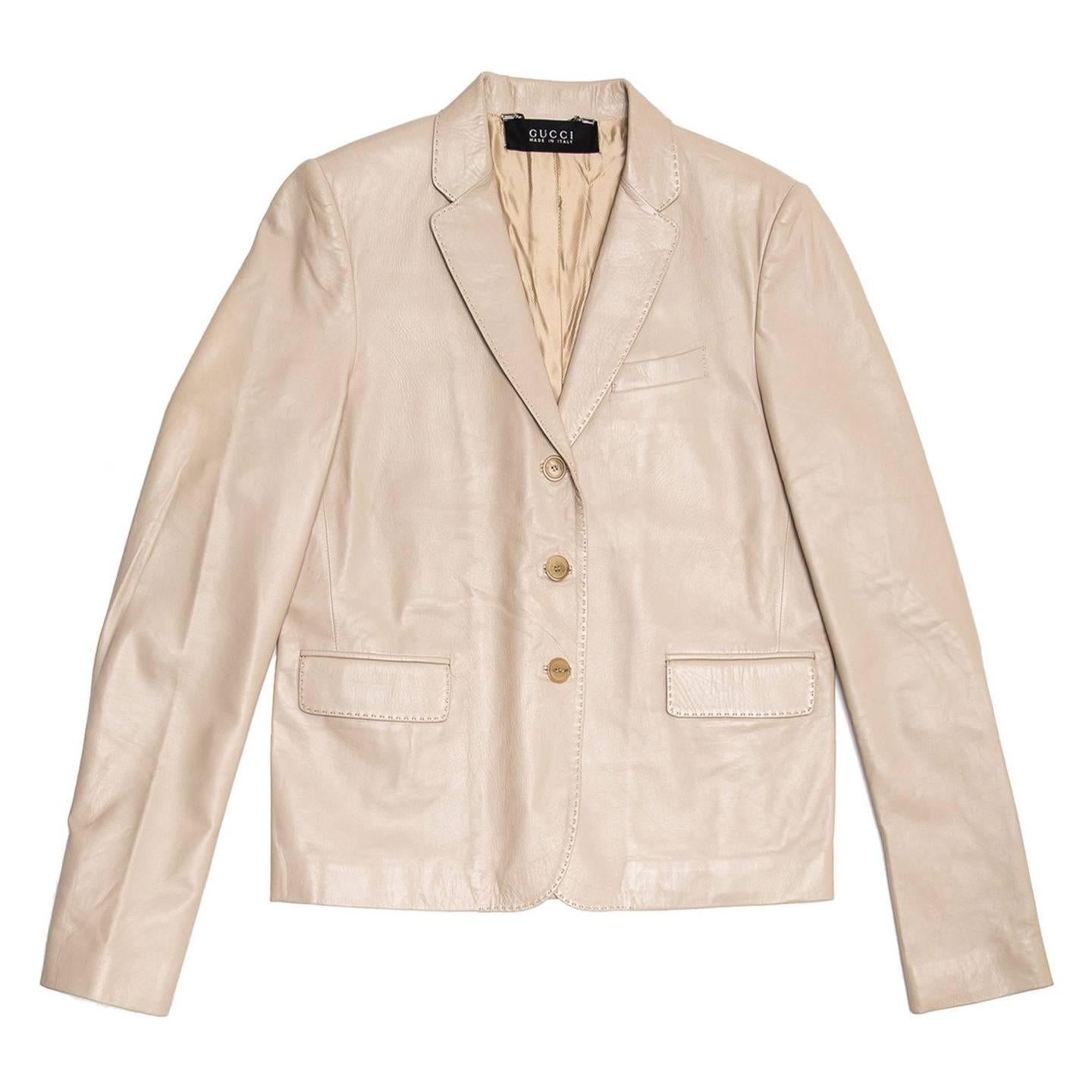 Khaki leather boxy jacket with small lapel, 3 button opening at front, a breast pocket and flap pockets at waist. The cuffs open with 3 light brown horn small buttons and the back has two vents. All the profiles on lapel, pockets and seams are