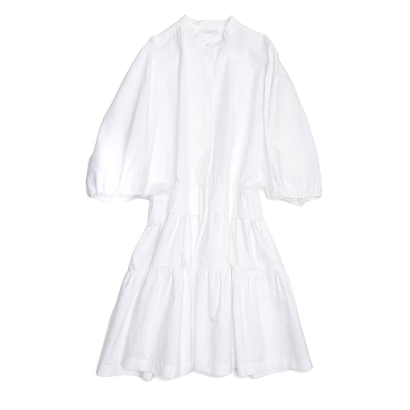 White cotton dress with Nehru neck, batwing sleeves and tiered layers. The top part fastens at front like a shirt and the buttons are covered by a flap, a drawstring regulate the waist line and back side seams create gathers on the sleeves. A deep