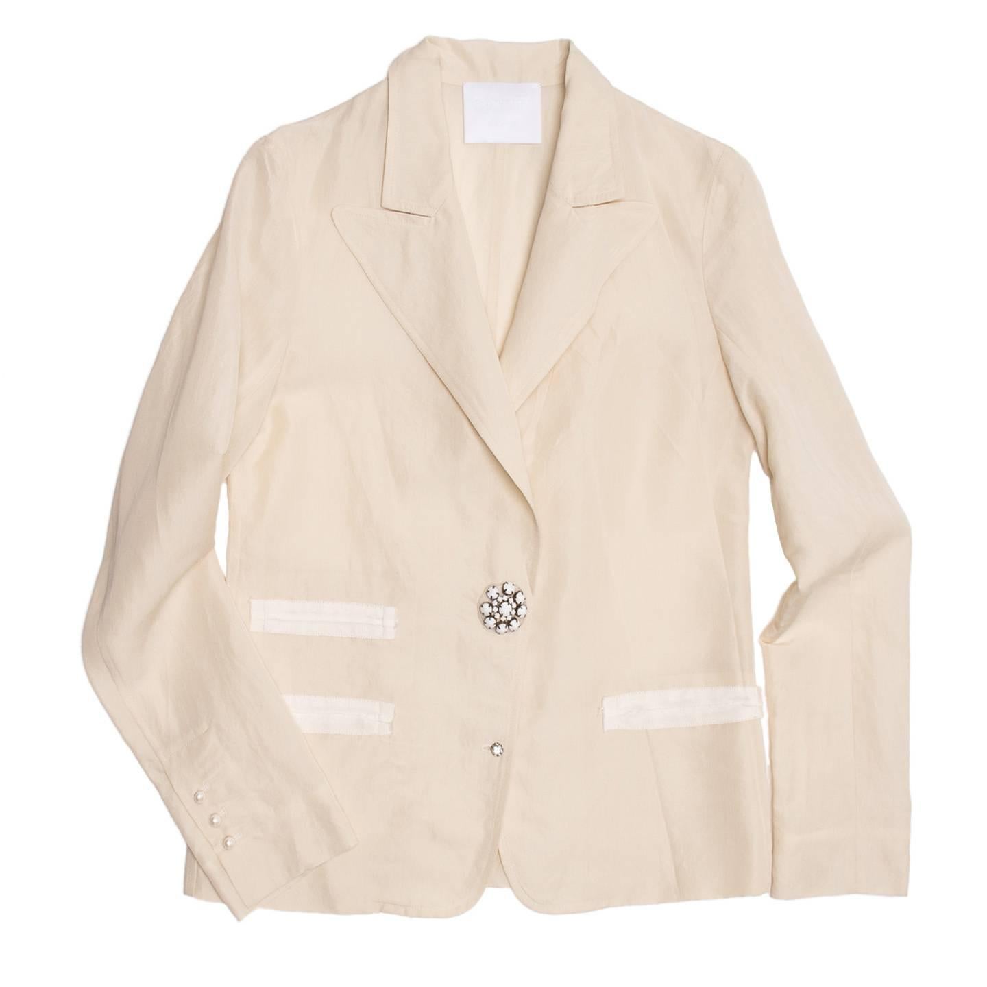 Lanvin 2008. Cream colored raw silk blazer with three slit pockets defined by ivory grosgrain ribbons. Small round perl buttons adorn the cuffs and a big white stone jewel button together with a little silver rhinestone flower button fasten and