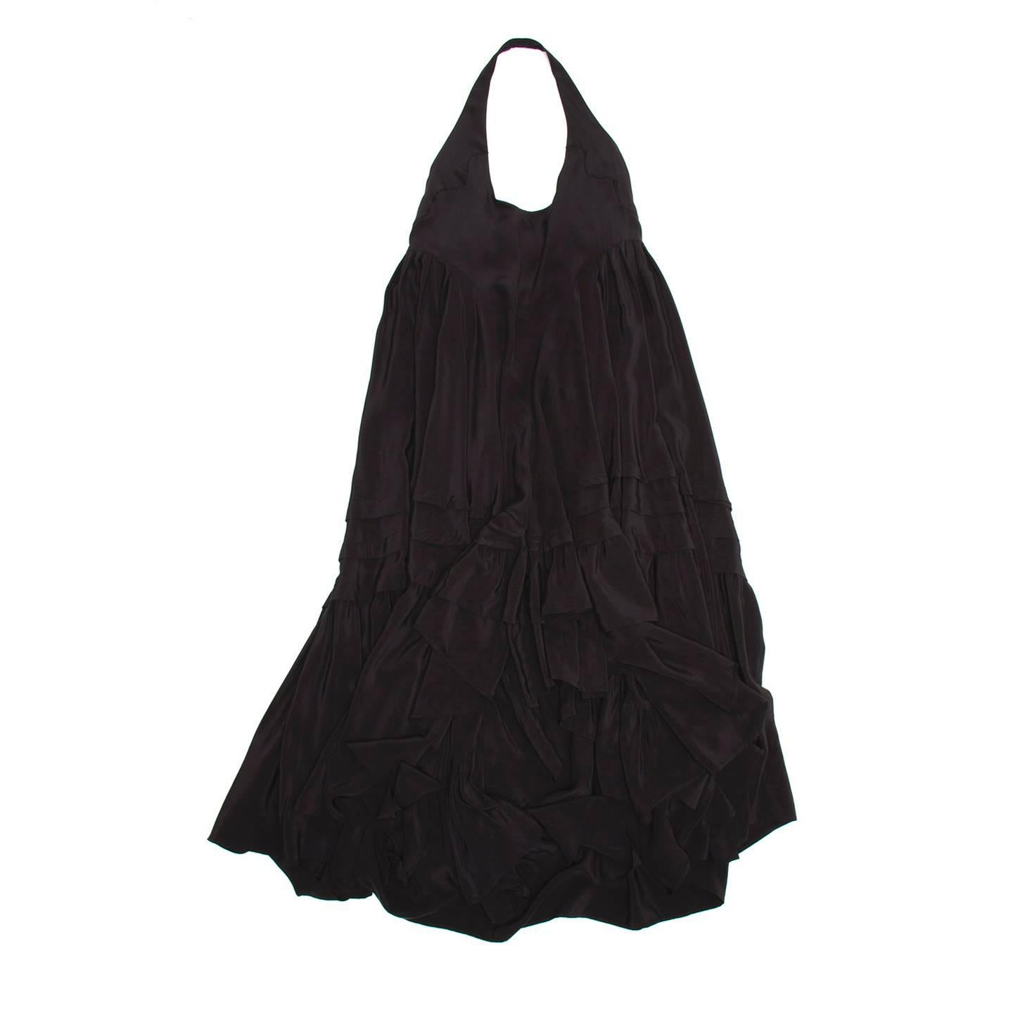 Black silk dress with halter neck and open back. The fit is very full, wide and flaring with a gathered bottom layer; the hem is longer at back to the ankle and at front it is below the knee.

Size  42 French sizing

Condition  Excellent: worn a