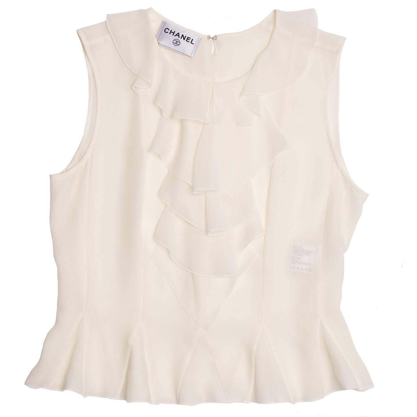 Ivory silk chiffon sleeveless top with a feminine peter pan neck and ruffle bib front detail. Triangular inserts on hem reproduce the flair of the ruffles and elegant little perl buttons fasten the back.  Attached CC Placket

Size  42 French