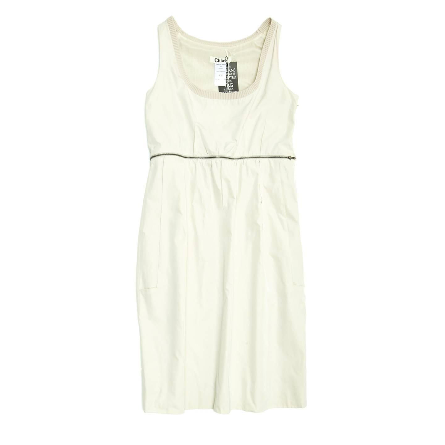 Silk ivory sleeveless dress with silver metal zipper to underline the empire waist line all around the dress. The scooped neckline is embellished with a ribbed border at front and back, at back armholes and the back top panel is made of ribbed knit