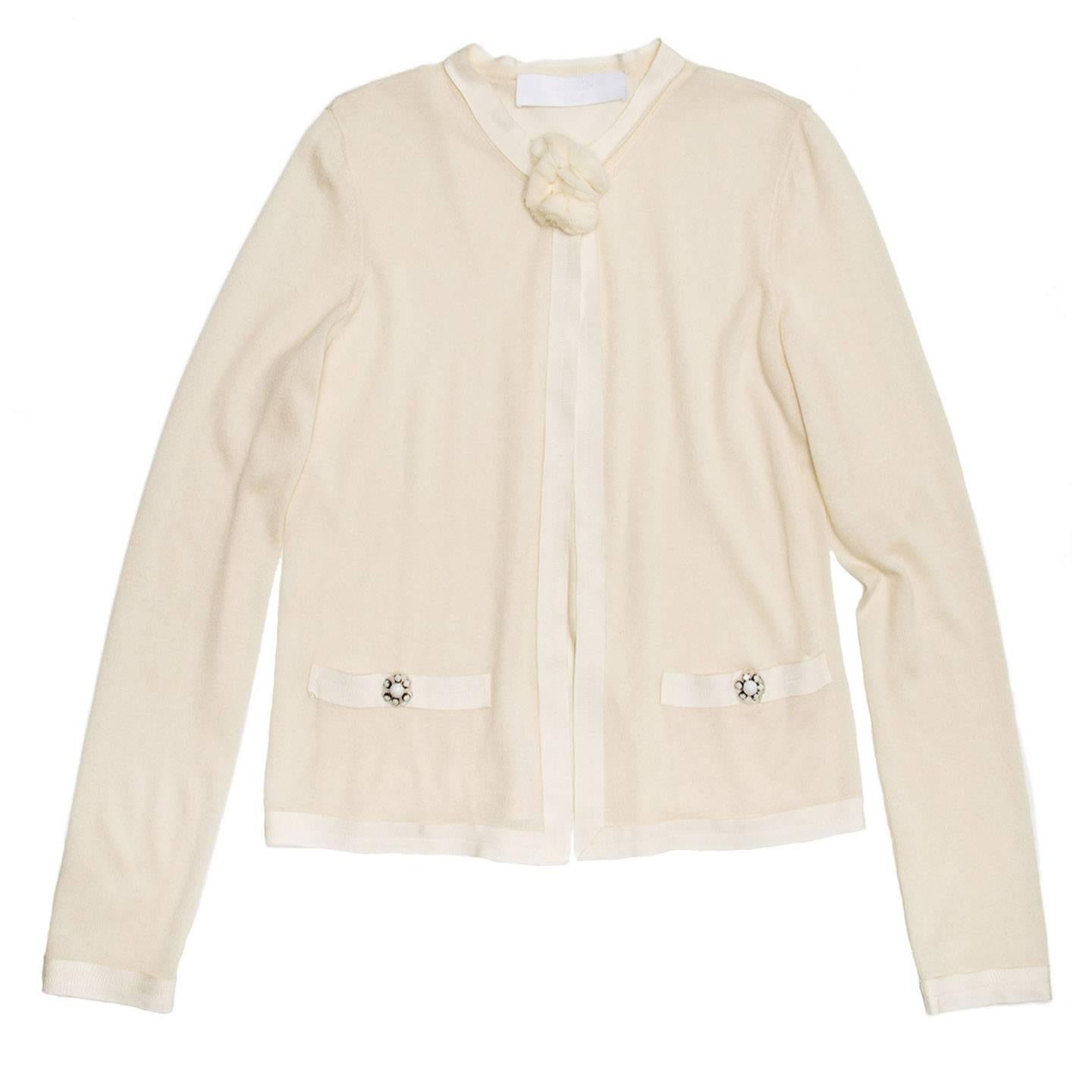 Ete 2008 cashmere and silk bland ivory cardigan with grosgrain profiles and pockets top edge. The front fastens with a chiffon flower button at neck only and jewel white rhinestone flower buttons embellish the pockets.

Size  XL Universal