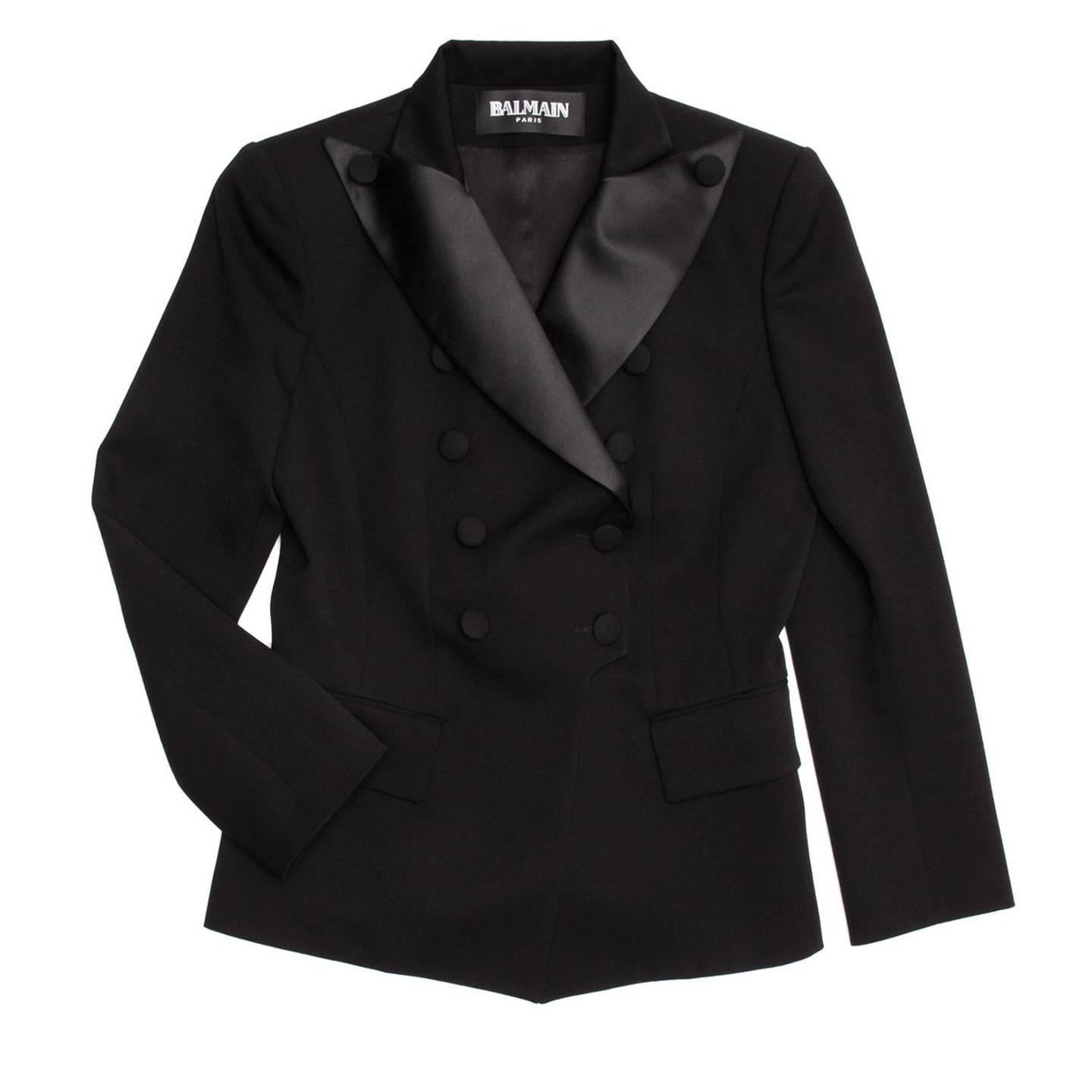 Black wool tuxedo style jacket tapered at waist for a feminine fit. Double breasted closure with wide satin lapels and wool covered buttons.

Size  44 French sizing

Condition  Excellent: worn a few times