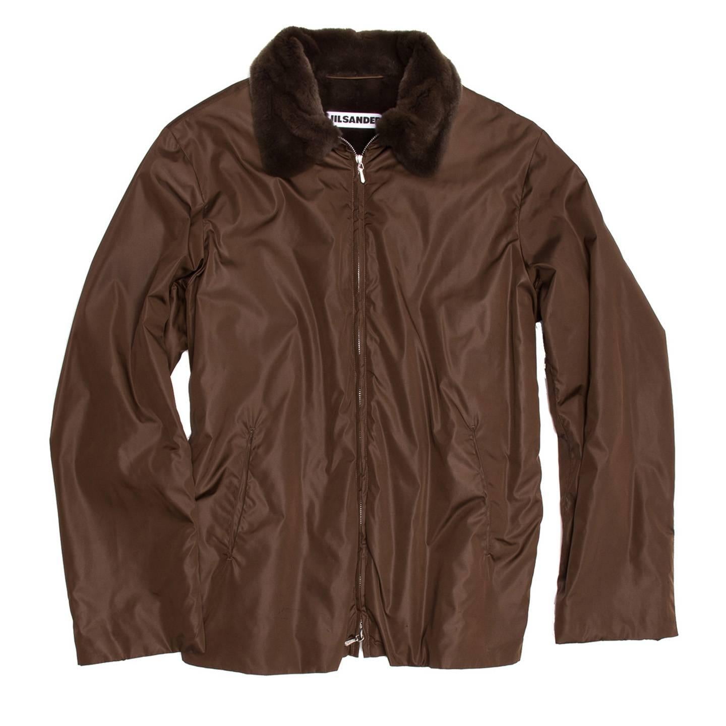 Fitted brown nylon and beaver fur jacket with a metallic open ended front zip. The beaver fur covers the inside body, the sleeves and the peter pan neck. Two small brown and metal short zips were applied on the sides to regulate the hips