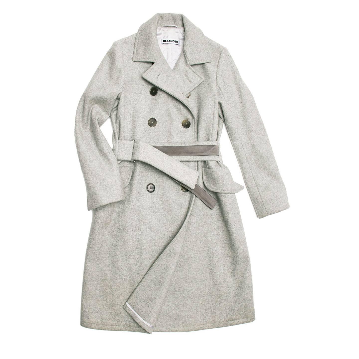 Knee length double breasted ice grey coat with 2 pocket flaps at front. Leather trim at collar stand and atop of belt. Belt loops slides through belt loop and D-ring at waist.

Size  42 French sizing

Condition  Excellent: worn a few times
