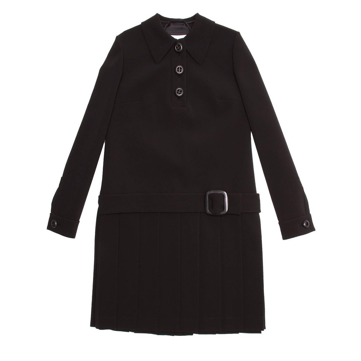 Black thick triacetate/polyester blend 60's style dress with open back and pleated skirt. The shirt collar is quite wide and pointed, the front opening stops at bust and fastens with three large black buttons. The dress has a straight line with a