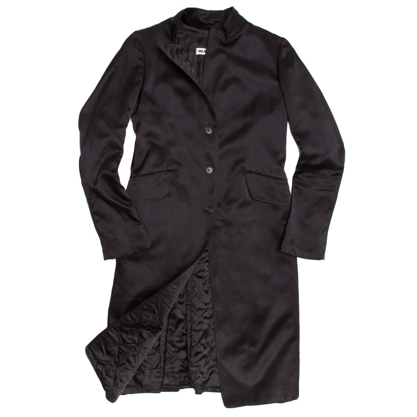 Long black silk satin 3 buttoned evening coat. 2 wide flap pockets at front side. Seams at back have pleats which flare out for a nice feminine touch to a classic tailored coat. Diamond quilted lining.

Size  40 French sizing

Condition 