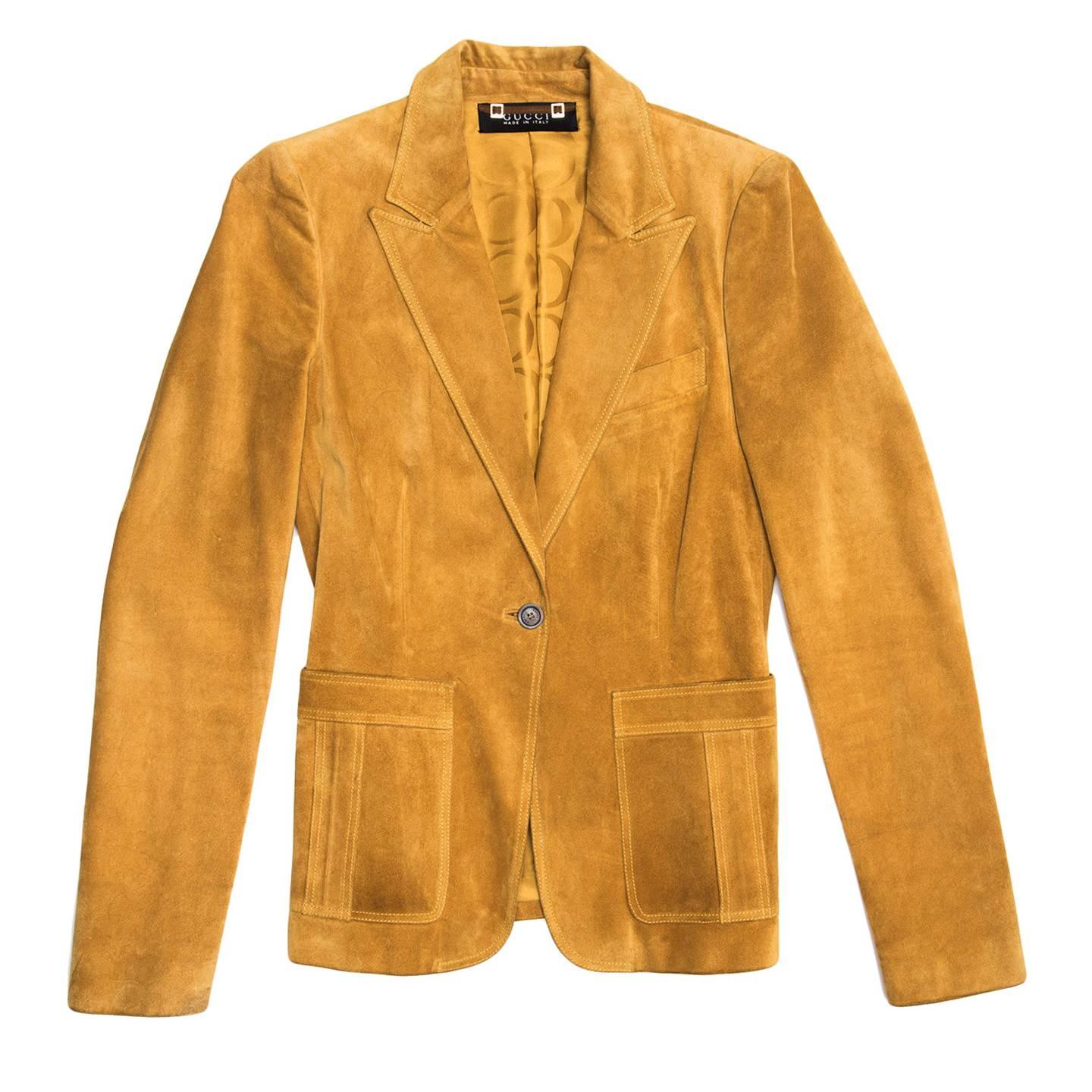 Ochre color suede single breasted jacket, blazer cut, with peaked collar, breast pocket and bellow patch pockets at hips. The single button at front and the buttons at cuffs are made of dark brown corn to create contract with the body color. Made in