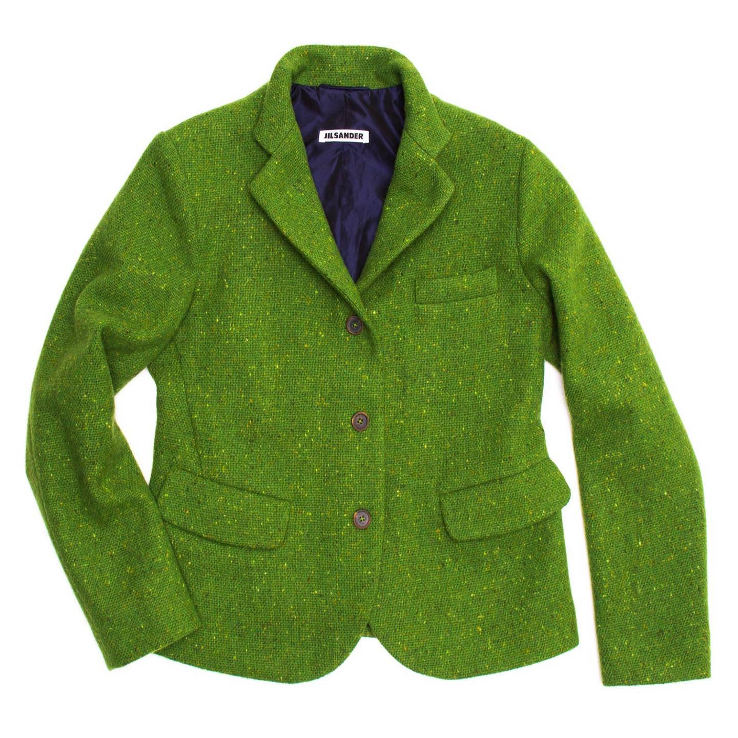 Bright green virgin wool tweed short blazer with three brown buttons closure and small lapel. The single breasted front has a round shaped hem at center front, two flap pockets sit at waist and a slit pocket at breast. Made in Germany.

Size  42