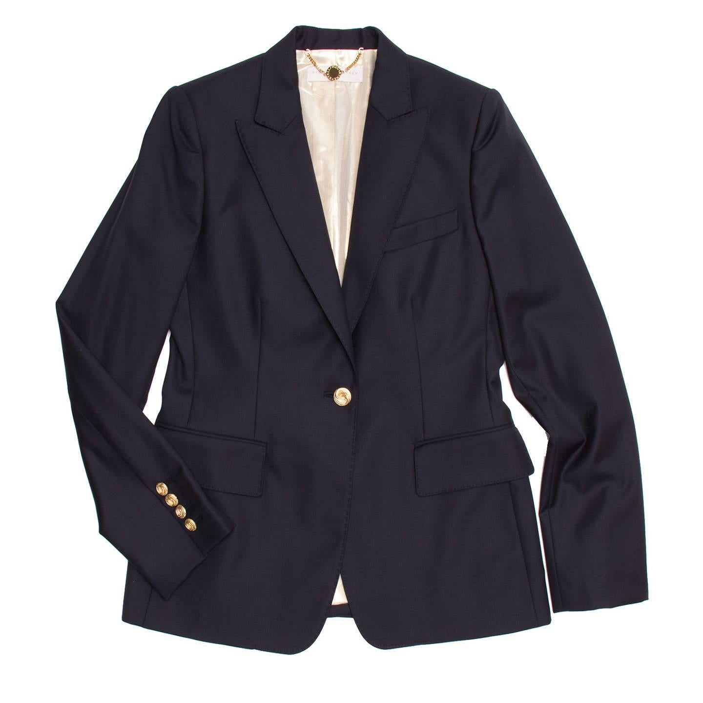 Navy wool single button tailored blazer. Gold buttons at front opening and at back of cuffs. 2 flap pockets at front and handkerchief pocket at chest. Pick stitching detail around the lapels. Vent at center back bottom. Chain hanger loop with logo
