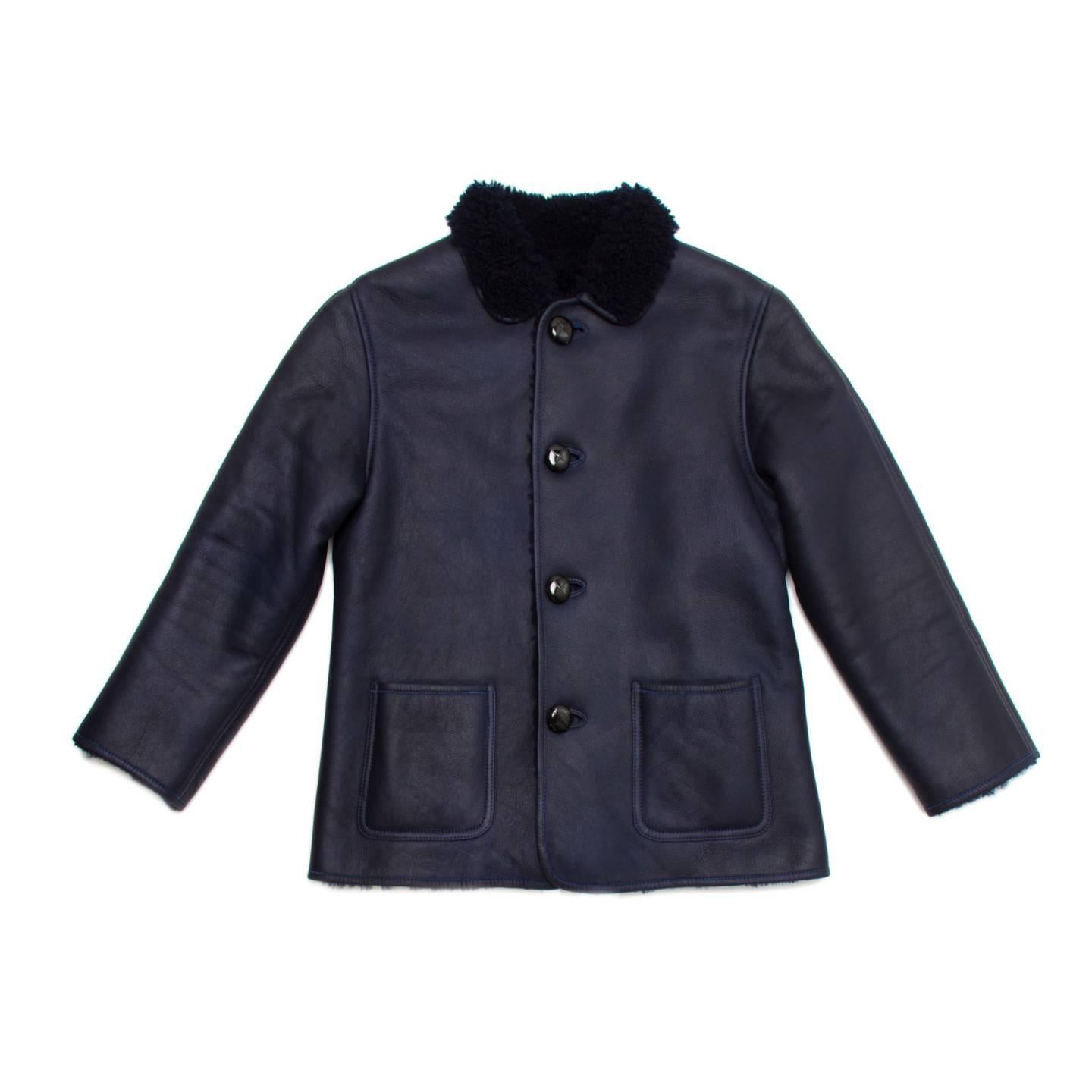 Midnight blue reversible lambskin hip length coat with peter pan collar. Black patent leather buttons fasten the center front on the suede side, while when worn on the fur side the buttons are tone on tone. Two rounded patch pockets enrich the front