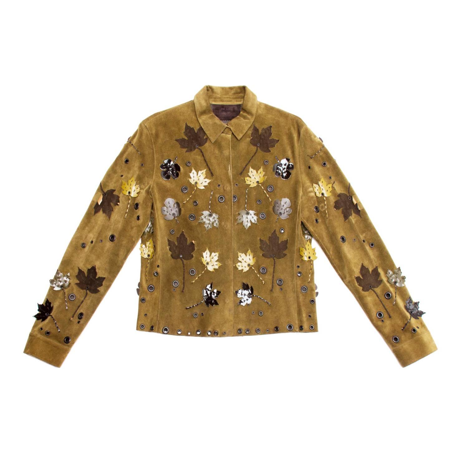 Collection piece musk green suede shirt jacket fully decorated with dark metal eyelets and leather leaves appliques. The jacket is not lined and it fastens at center front with hidden snap buttons, as well as the cuffs. The leaves appliques have