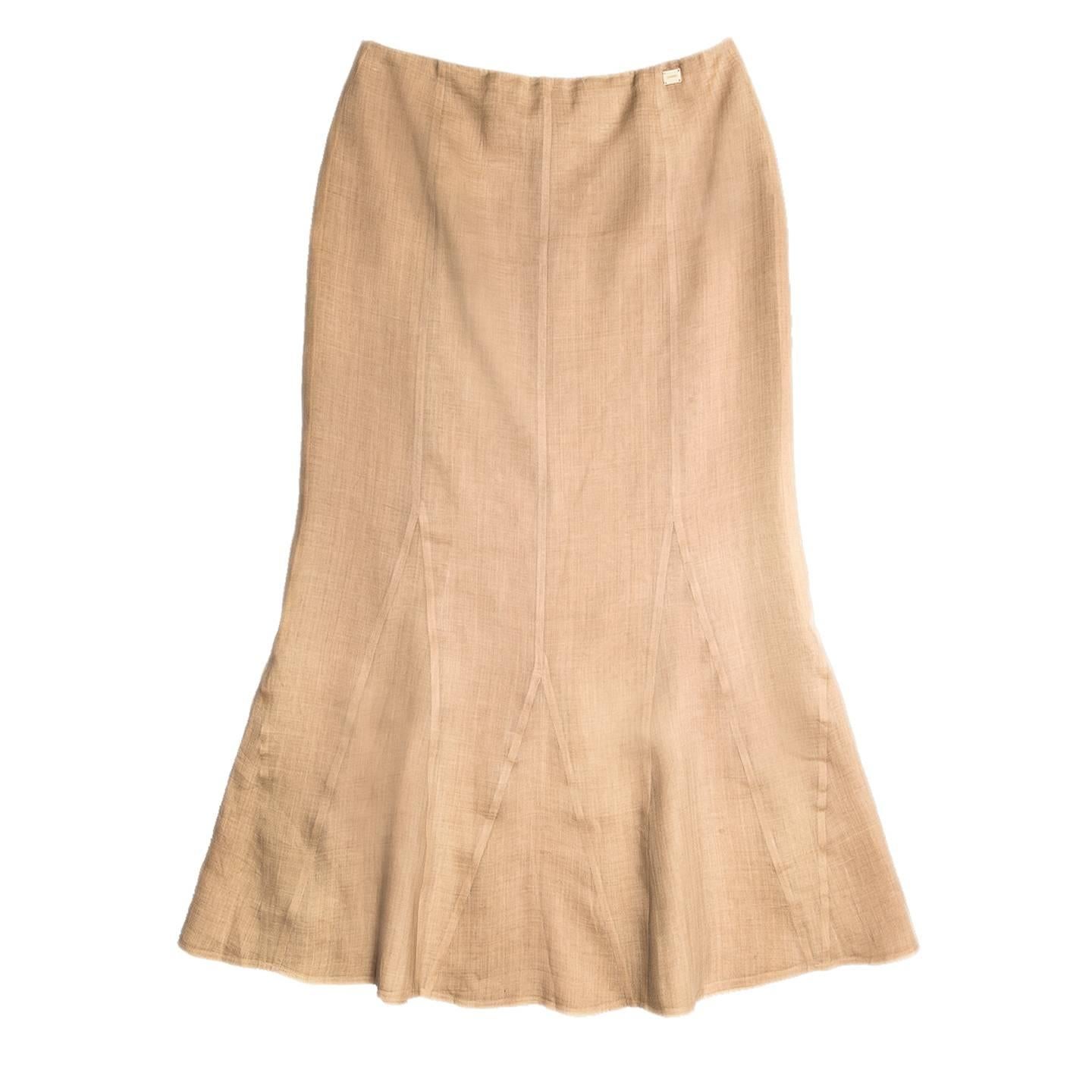 Ankle length tan ramie skirt fitted from waist to knees, with flare at hem thanks to the godet inserts. The color is natural echru, the fabric light and a sheer, for this reason the skirt is composed of two layers. A small Chanel placket is sewn at