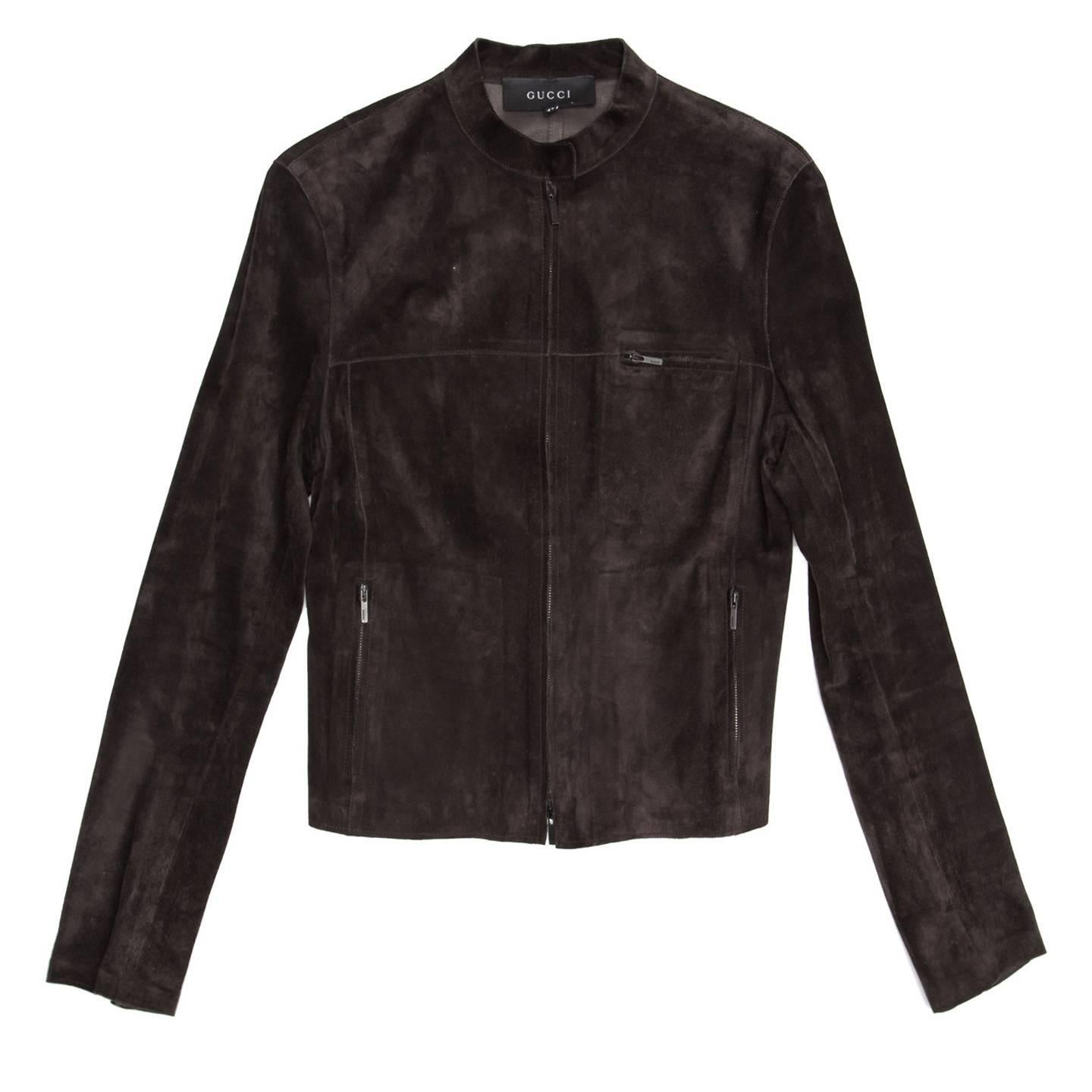 Chocolate brown suede cropped jacket with open ended metal zipper at center front and standing collar that fastens with a dark metal snap button. More metal zippers enrich the pockets at waist, the breast pocket, the cuffs openings and the back