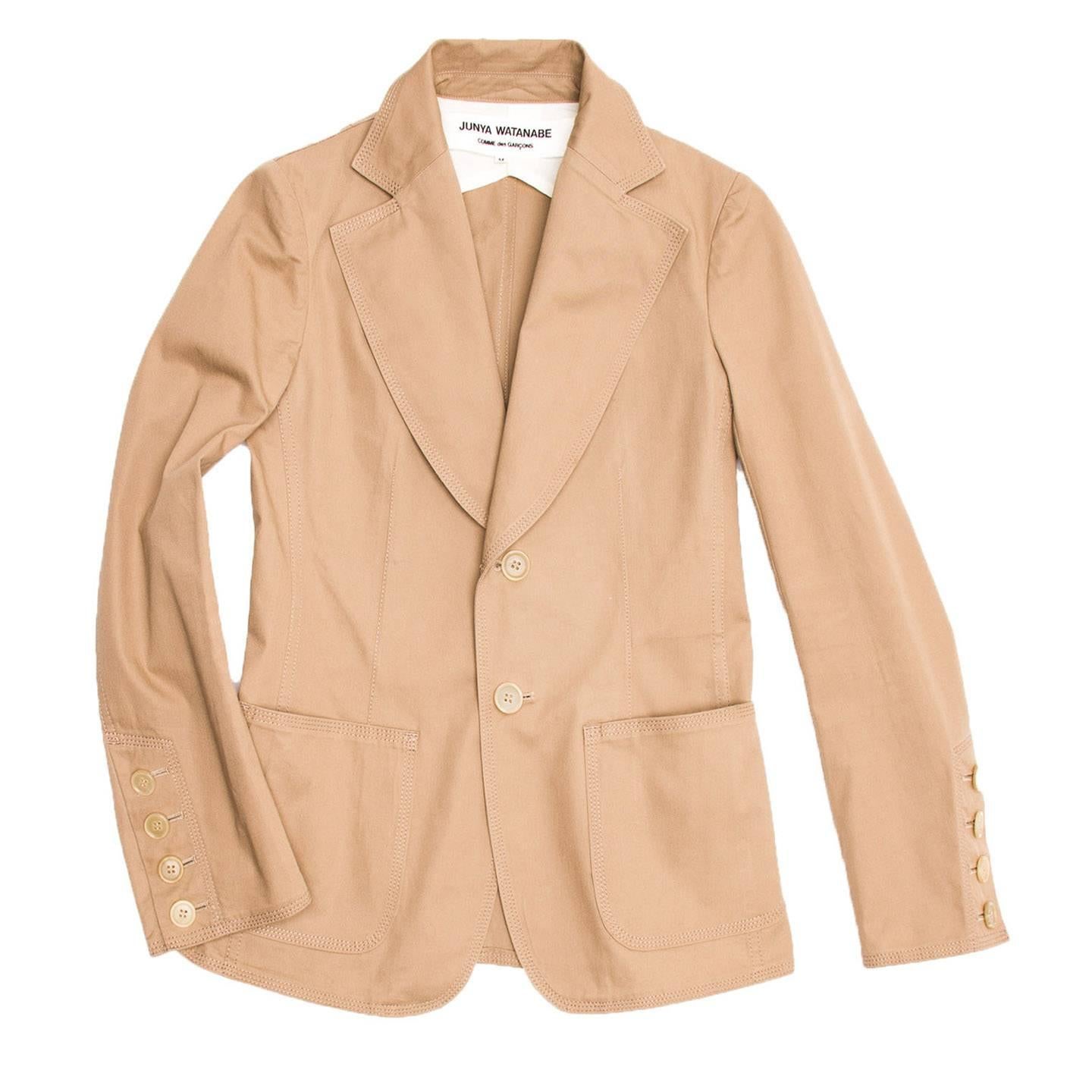 Tan cotton fitted blazer jacket with wide lapel. Patch pockets applied at front. Cuffs opening with four cream color buttons. Top stitches tone on tone decorate seams and profiles. Designed for Comme des Garçons.

Size  M Univarsal sizing

Condition