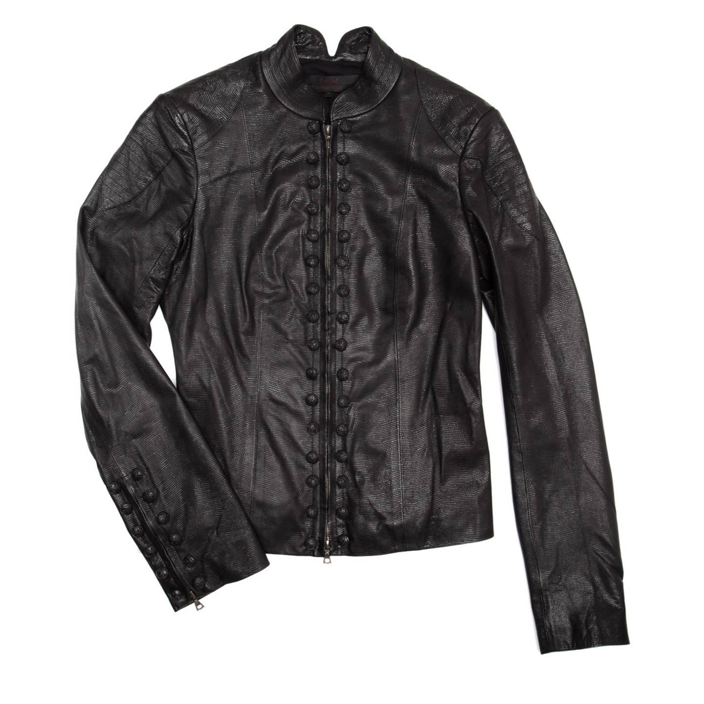 Black embossed leather motorcycle style jacket with patch details at shoulders and top sleeves enriched by top stitching as well as the standing collar and the lower back panel. The fit is cropped and tight, the front fastens with a bronze chunky