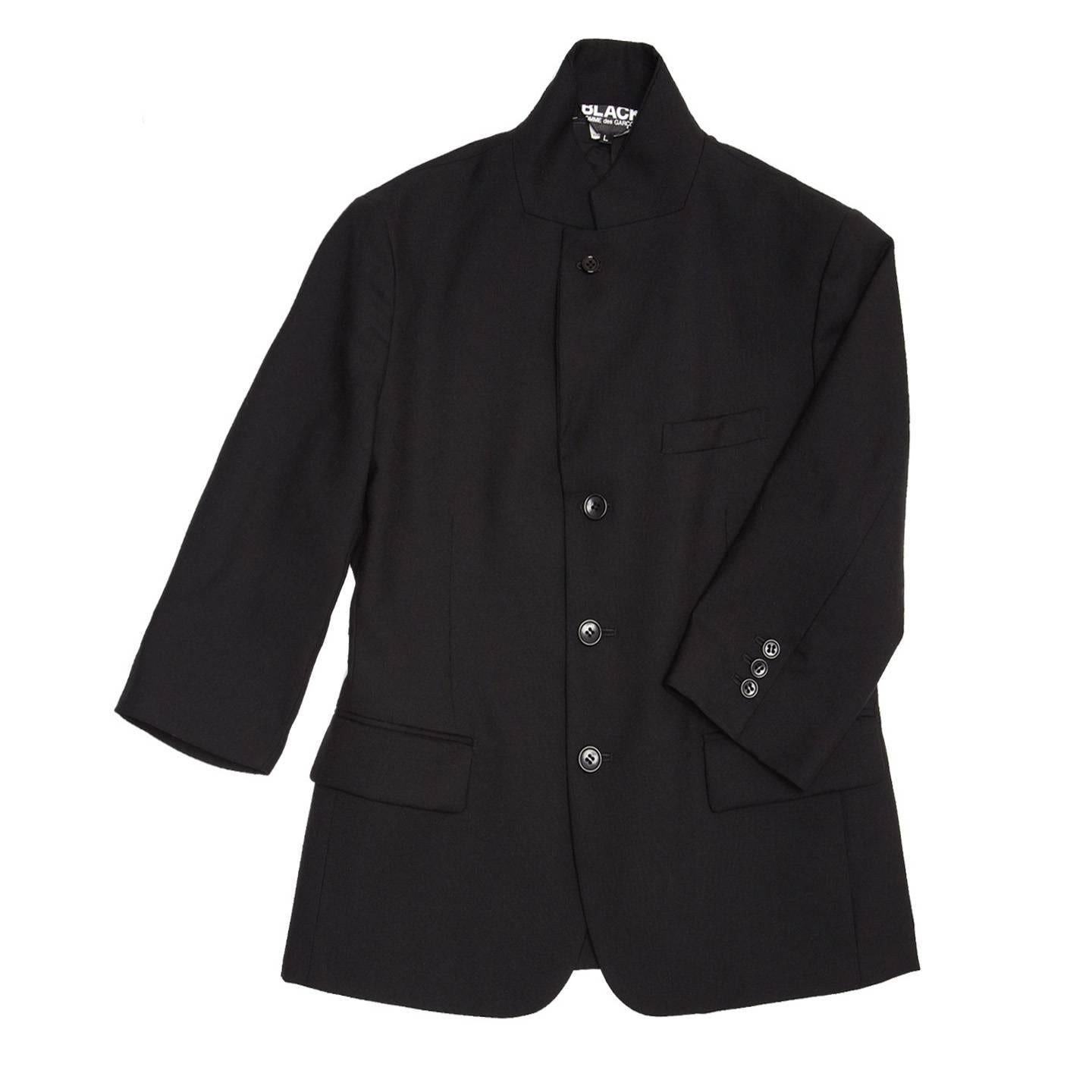 Black wool 3 buttons blazer with small lapel that can be worn standing up as well. The sleeves are 3/4 length, it has a breast pocket and 2 flap pockets at waist and a vent at center back. It is a Japanese size Large - fits as a U.S. size