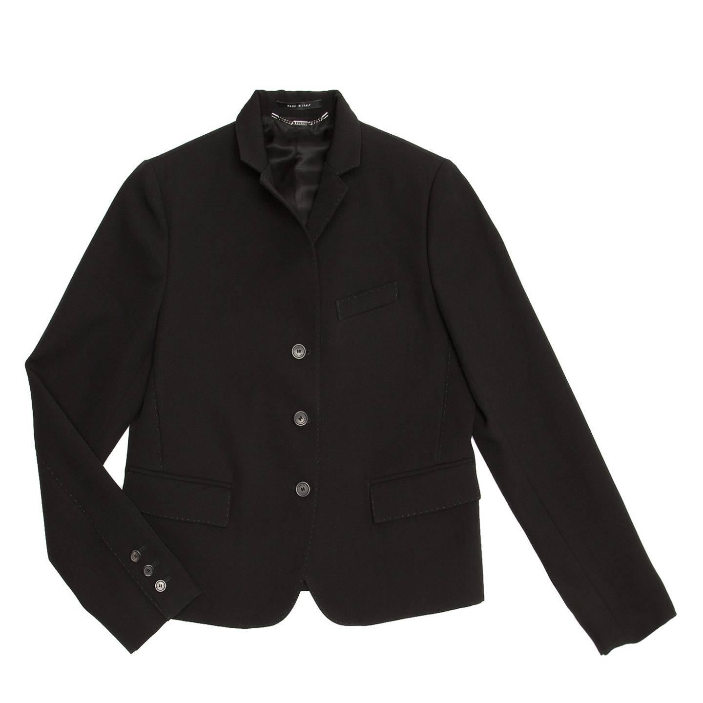 Black wool cropped jacket with a 3 button front opening and 2 back vents. The collar and lapel are small, can be worn folded or standing and are enriched by tone-on-tone hand top stitches. The waist pockets flaps, the breast pocket, darts and