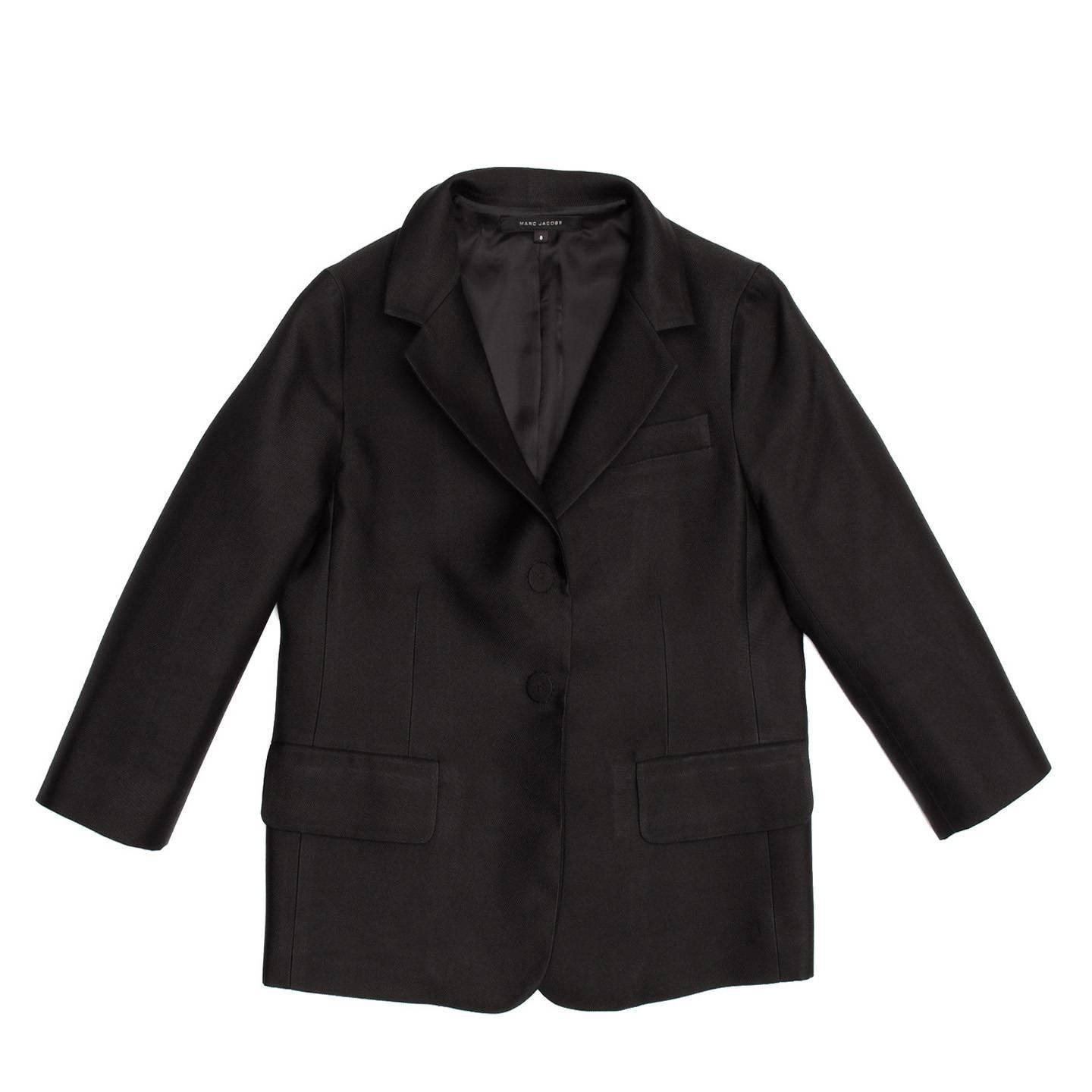Black silk shrunken boy style jacket with 3/4 length sleeves. Single breasted closure with two large snap buttons highlighted on the outer layer with beautiful thick hand stitches and elegantly covered with fabric in the inner layer. Single vent at