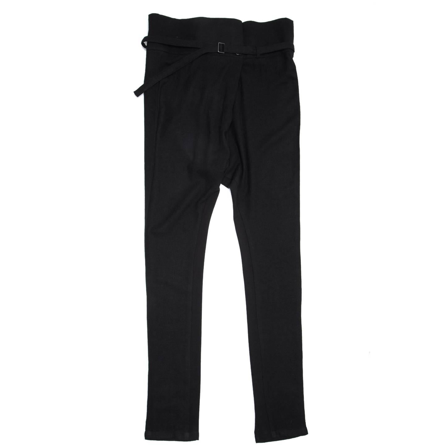 Black soft and thin virgin wool trousers with drop crotch and tapered legs. The waistband is wide and it folds in a big pleat at center front and fastens with a single button, creating more volume and movement. Small loops holds the thin belt at