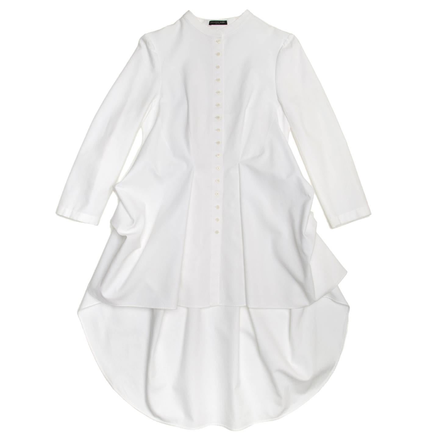 White Edwardian style pique shirt dress with mandarin neck and cuffless sleeves. The back reaches the mid calf and deep pleats create a wide volume, the front is enriched by two inverted pleats as well and the sides are bustled at under hips.

Size 