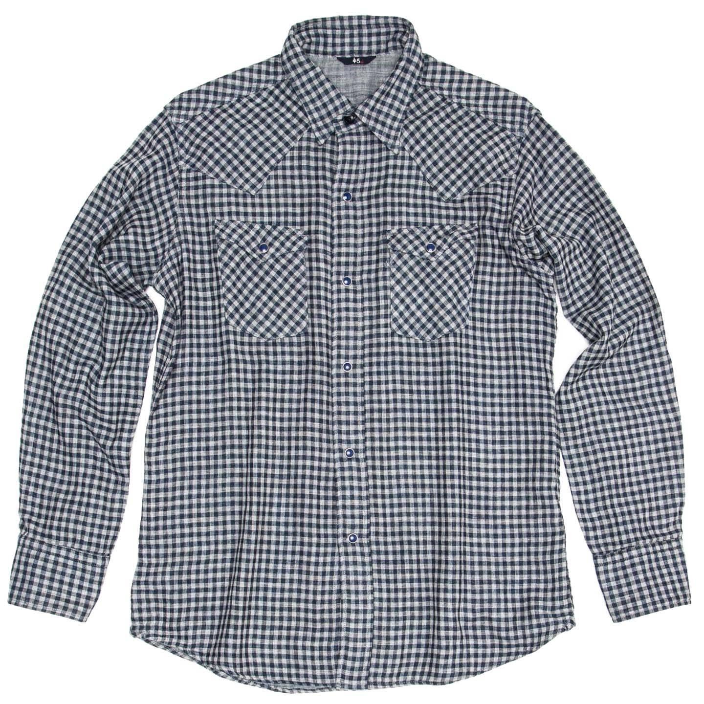 Fitted indigo and grey gingham soft cotton shirt with spread pointed collar with blue stone and metal snap buttons. The shirt has a western flair thanks to the shaped yoke at back and front. Two patch pockets with shaped flaps close with the same