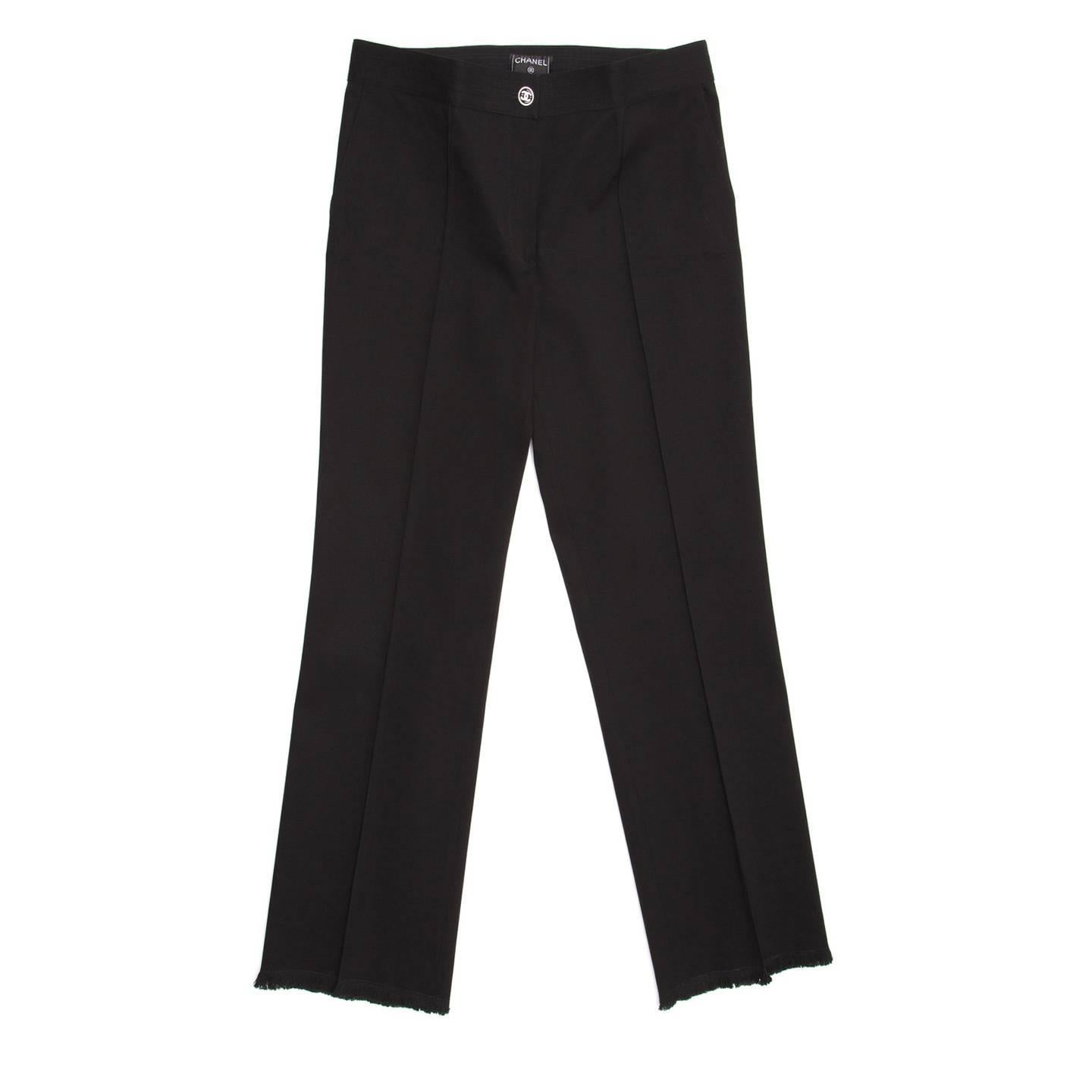 Beautiful fitting low waist black cotton/spandex trousers with vertical slash pockets at front and an horizontal slit pocket at back. The front is flat, the waist fastens at center front with a black and silver Chanel button, the legs are straight