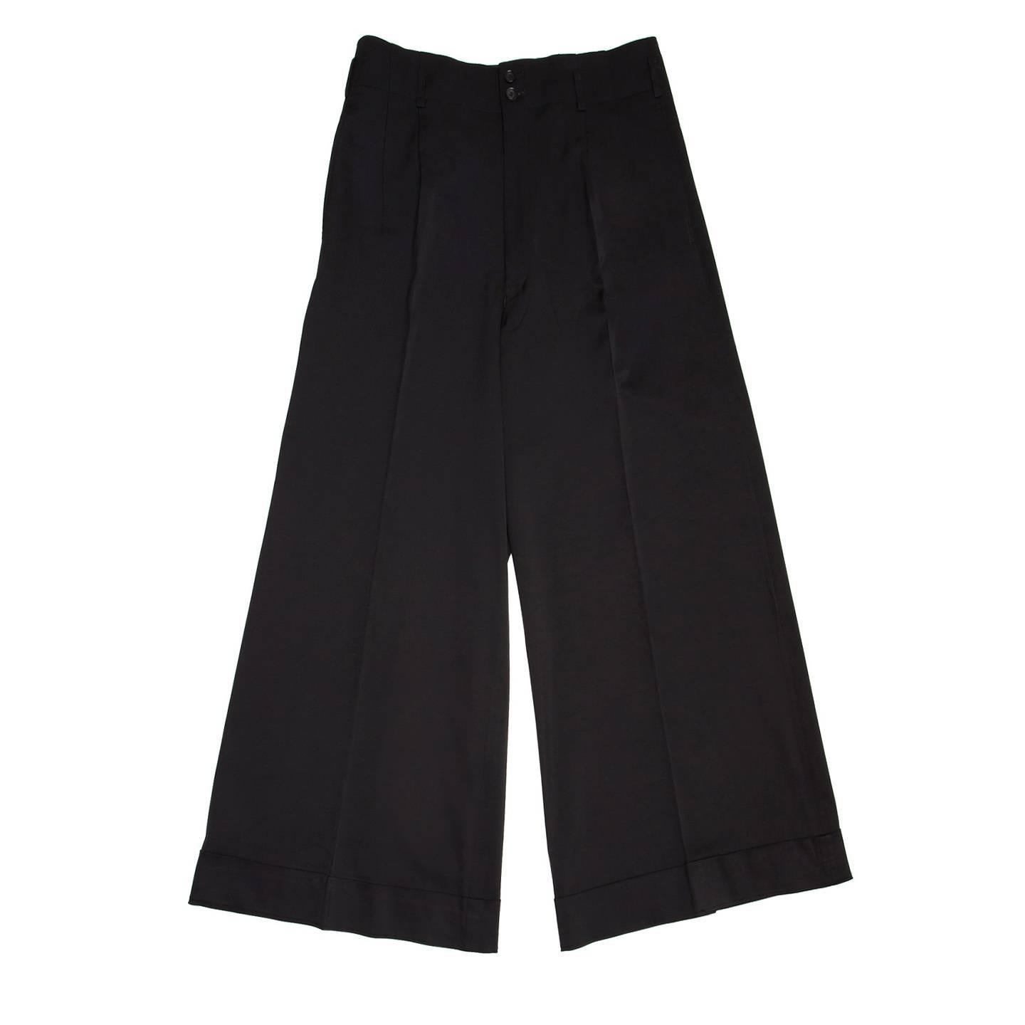 Beautifully made rayon pleated trousers with very wide legs. The waist has no band but a stitching line and small belt loops, the front slash pockets are at side seams and the back pockets are different: a slit pocket and a flap pocket fastened with