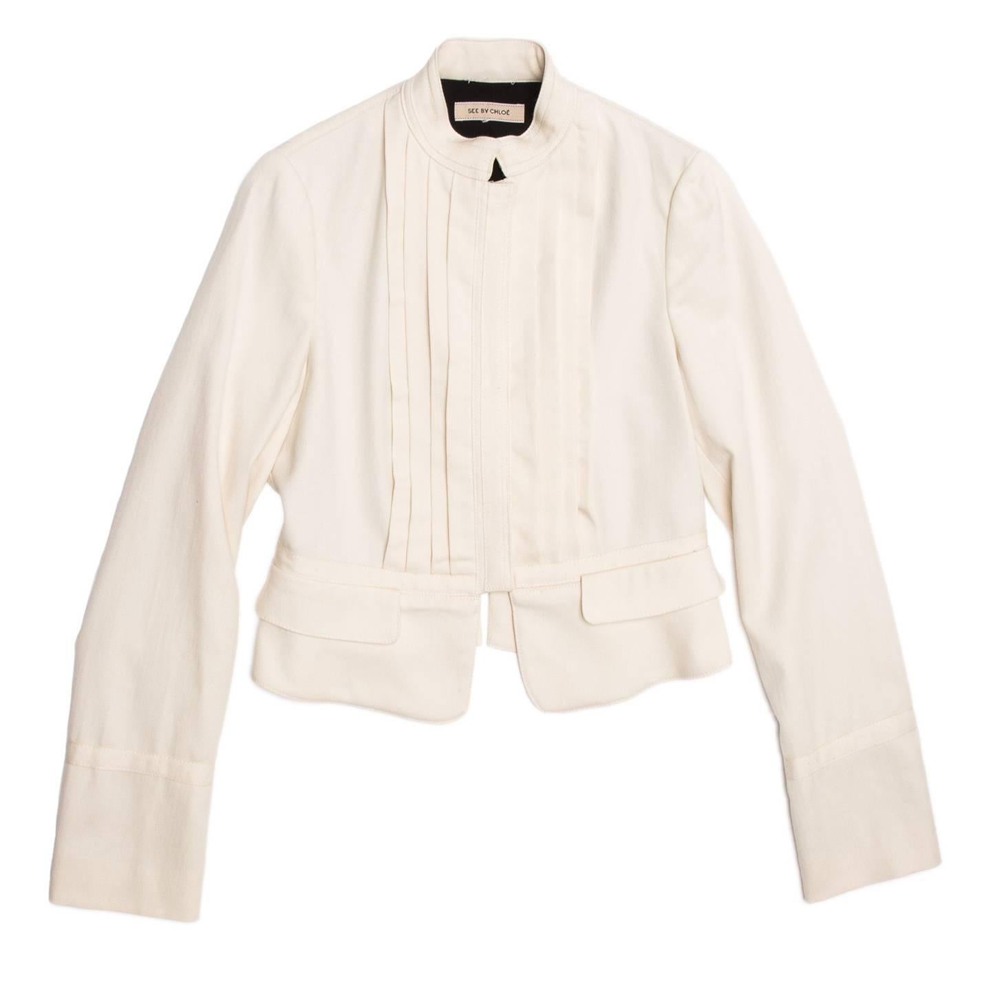 Cream wool/cotton cropped bellboy style jacket with pleated front detail and tone-on-tone binding on neck, cuffs, waist line, front opening and back seams. The jacket fastens at center front with concealed metal snap buttons.

Size  46 Italian