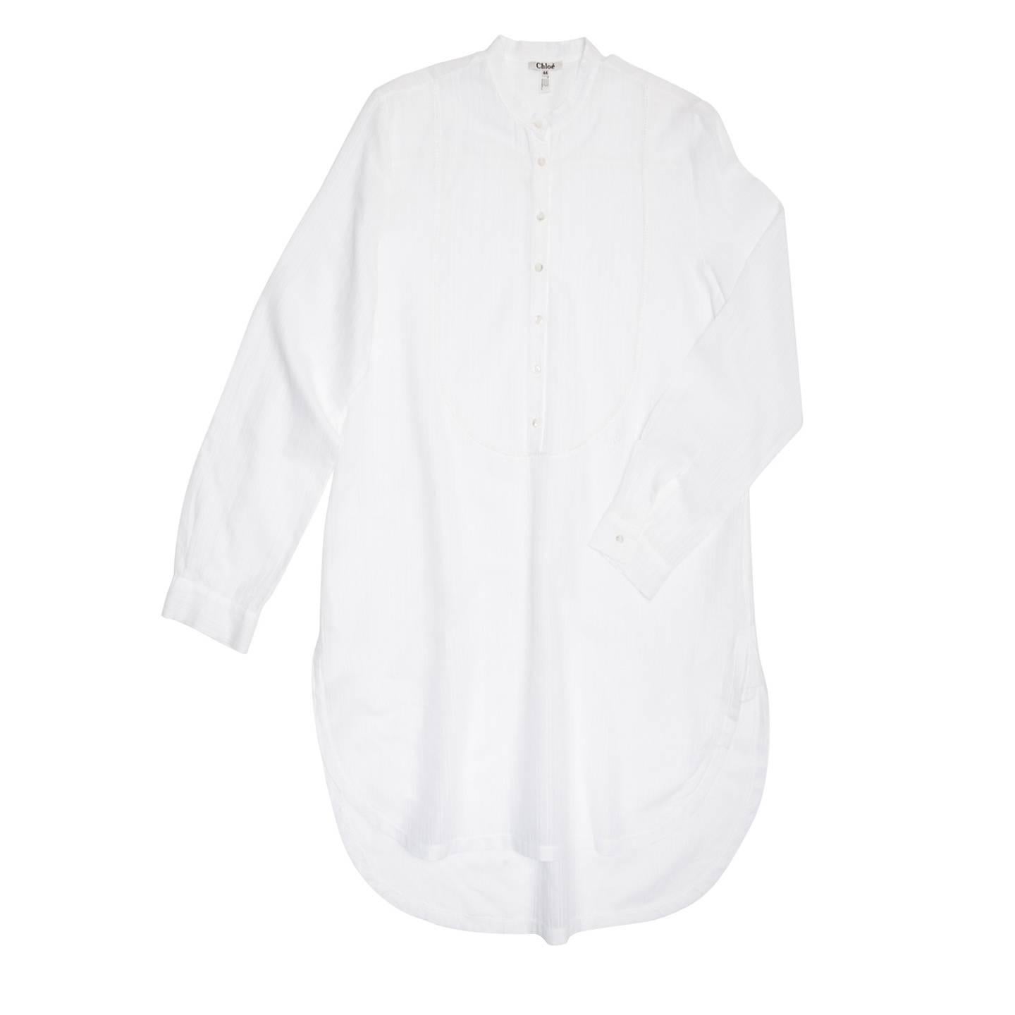 Beautiful white stripy jacquard tunic style shirt dress with Nehru collar and bib front designed by a small beautiful trim that enriches the back yoke as well. The hem is round with detailed vents at side seams and the back is longer than the front.