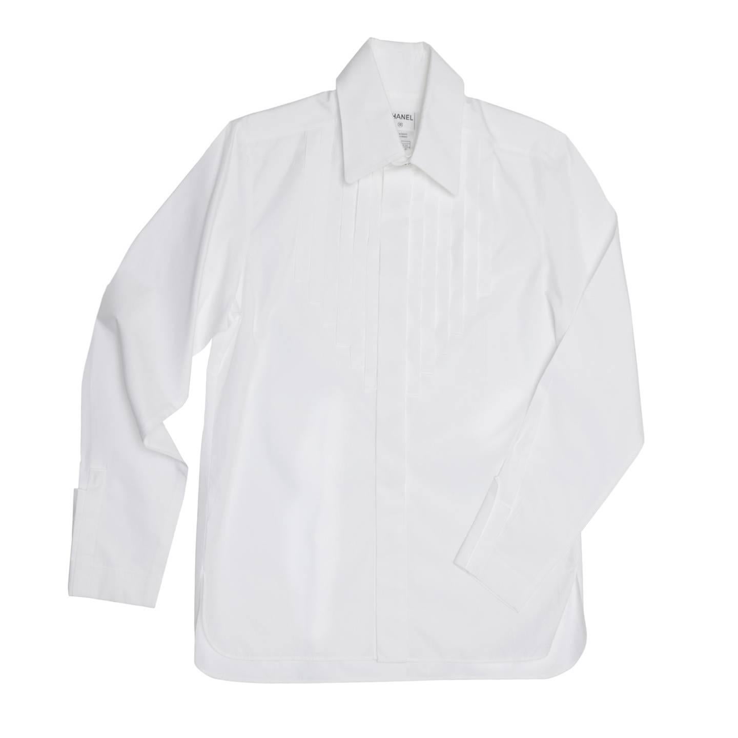 Pure white cotton shirt with large rounded peter pan collar standing on a higher neck that fastens with two white and metal buttons. The buttons at center front are hidden under a wide placket and a bib detail repeats this detail with vertical and